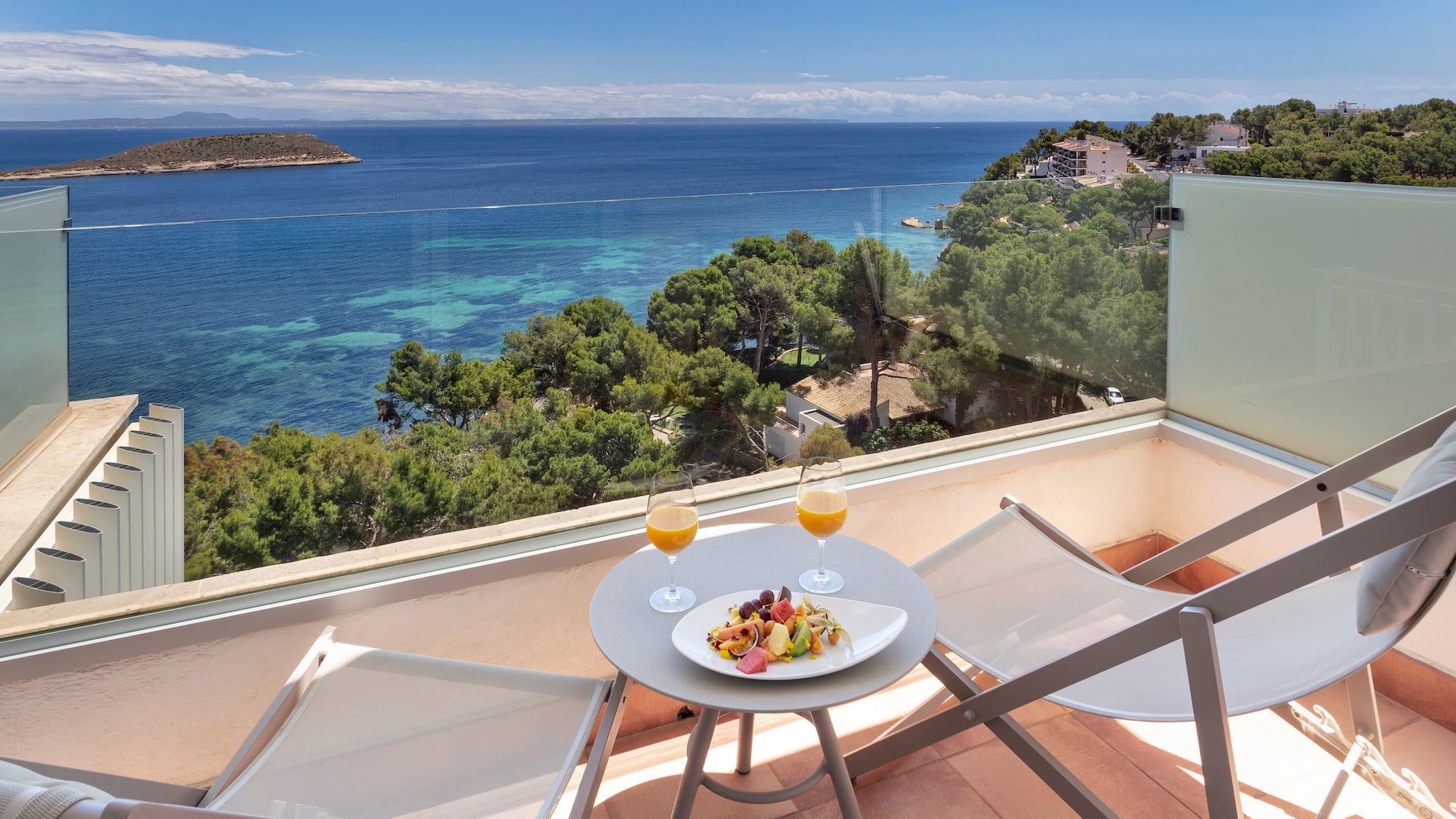 a table with food and drinks on a balcony overlooking a body of water