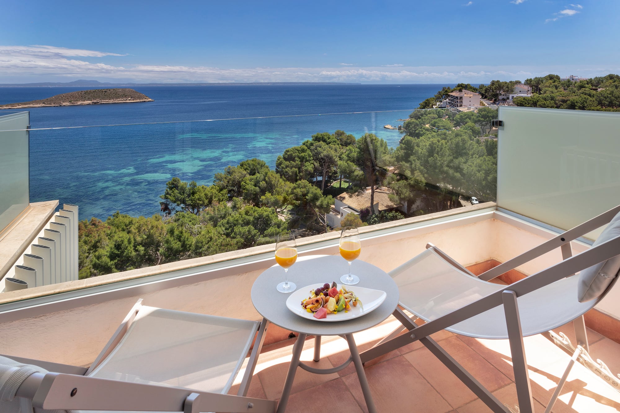 a table with food and drinks on a balcony overlooking a body of water
