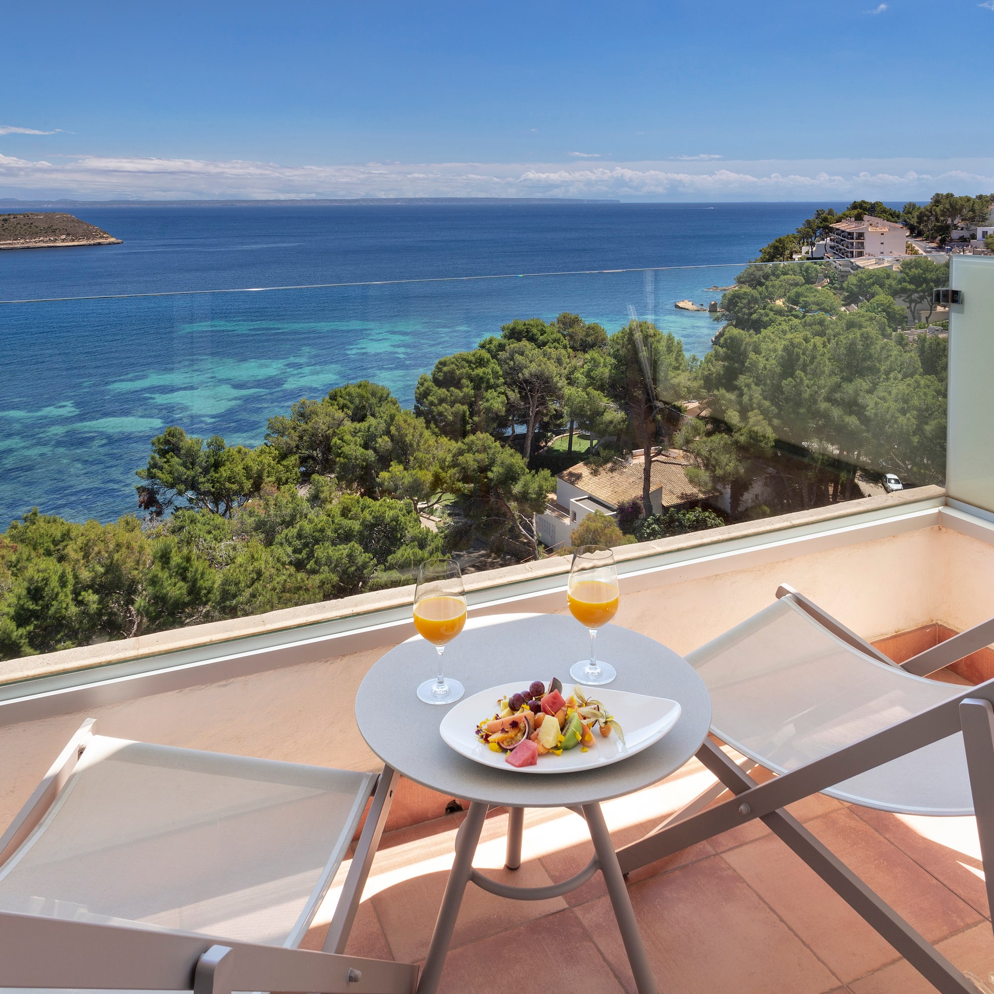 a table with food and drinks on a balcony overlooking a body of water