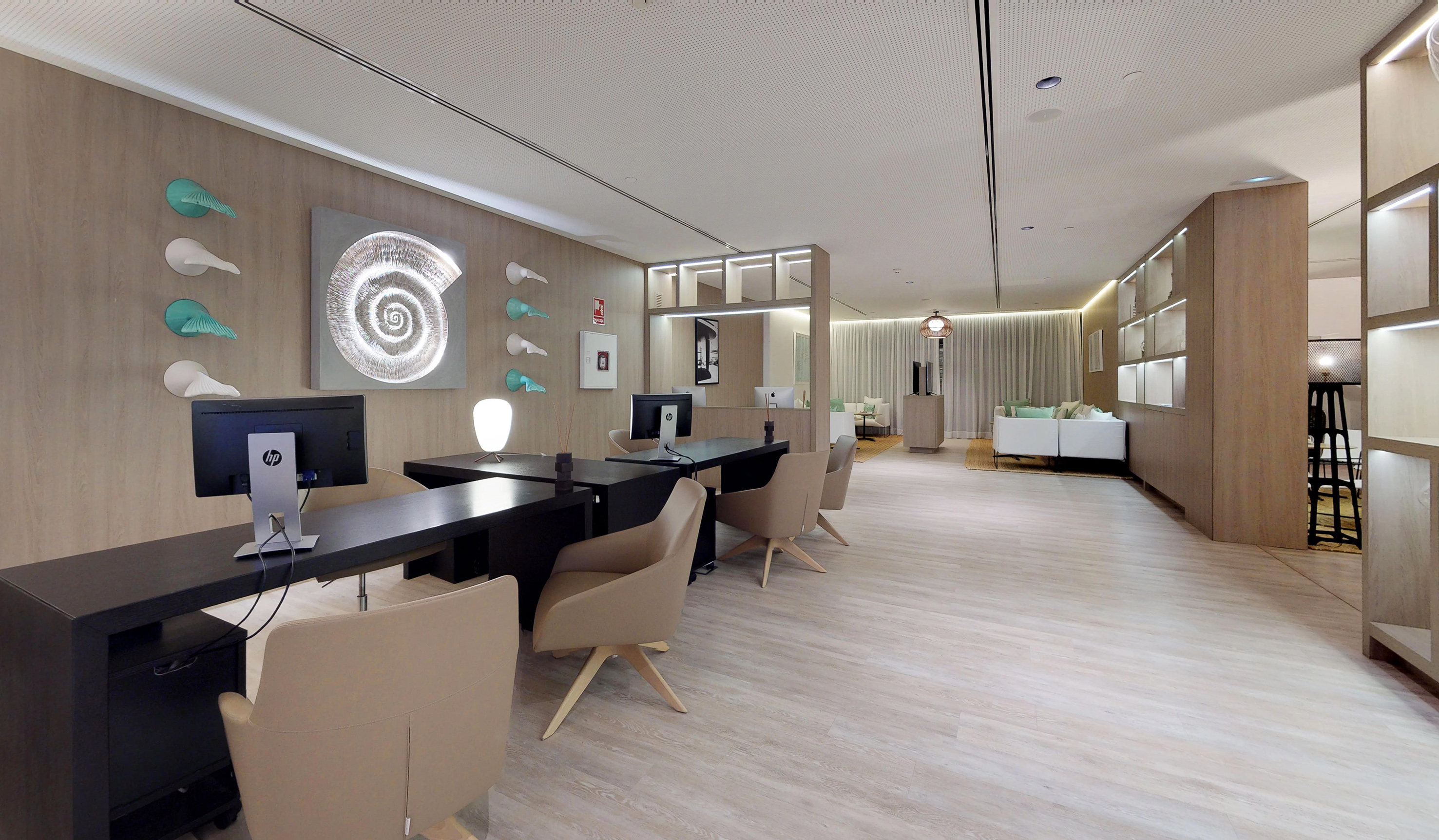 Contemporary reception area with desks, monitors, and modern shell wall decor.