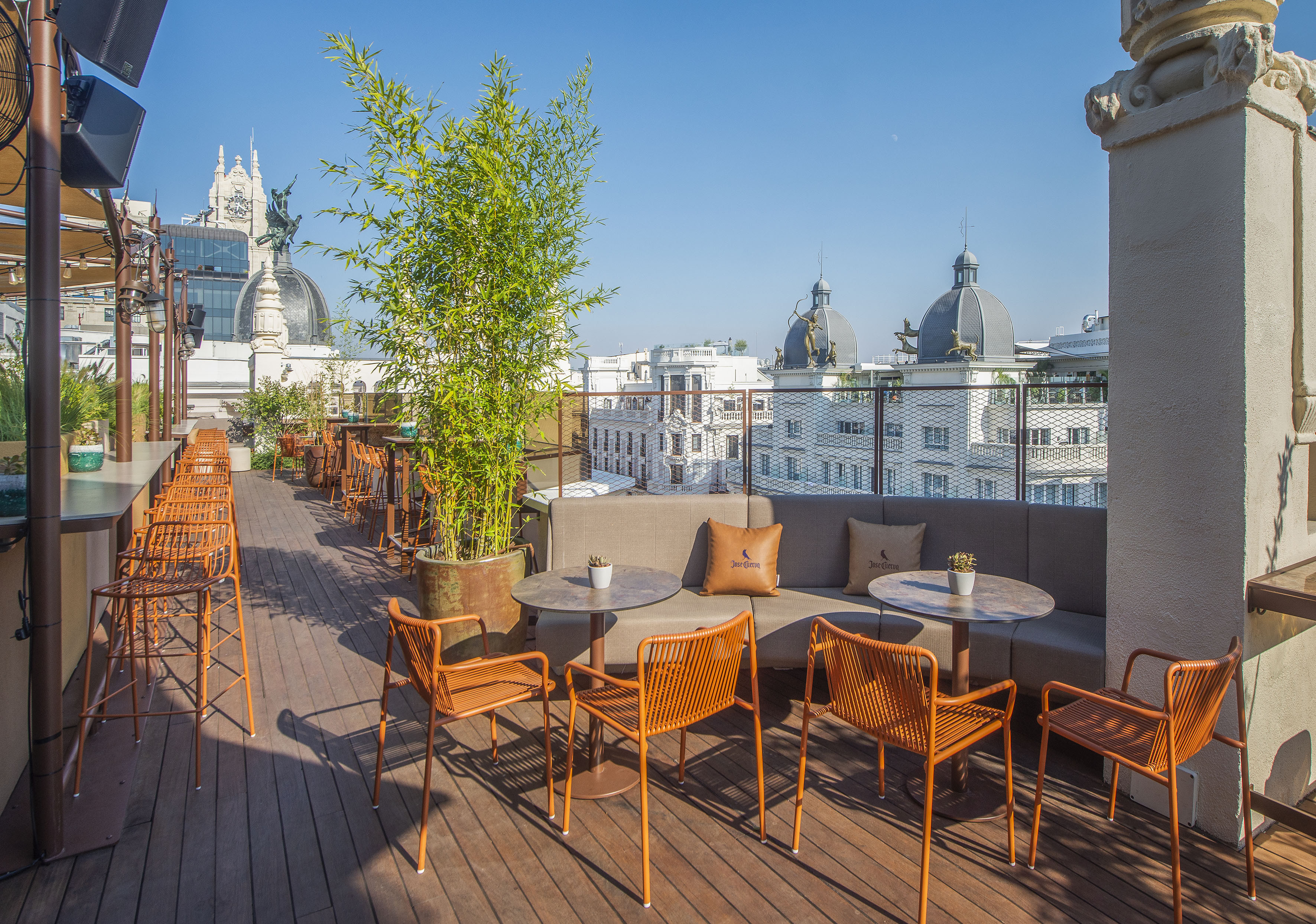 Sunny rooftop bar with comfortable outdoor seating and historic city skyline views.