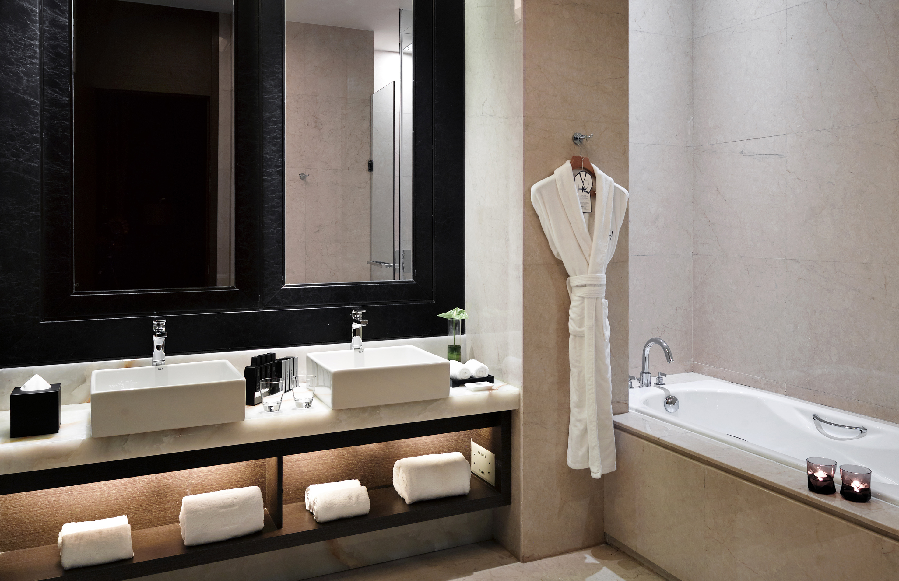 Luxury hotel bathroom with double vanity, soaking tub, and white bathrobe.