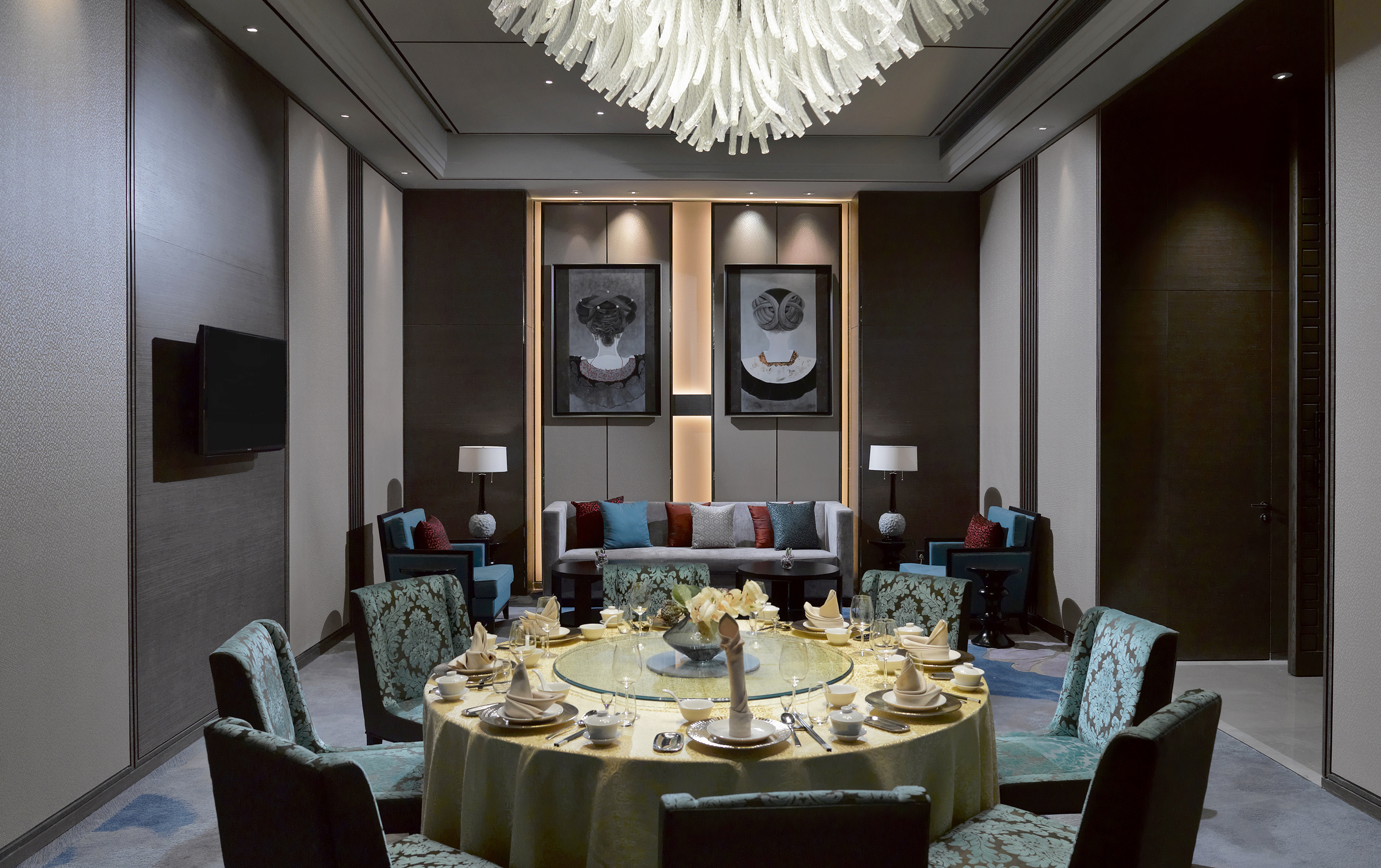 Luxurious private dining room with round table, chandelier, and modern decor.