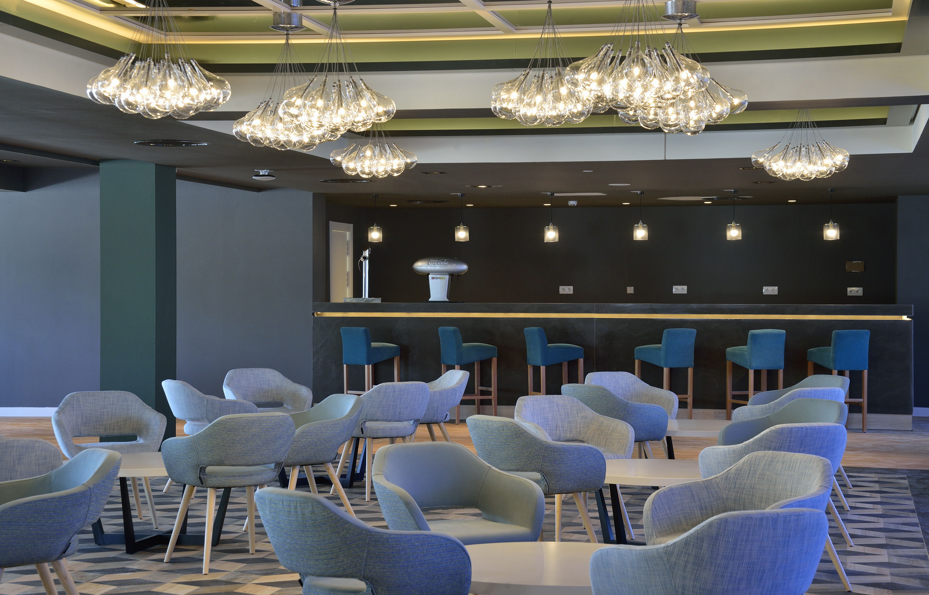 Modern hotel bar lounge with blue chairs and unique glass chandeliers.
