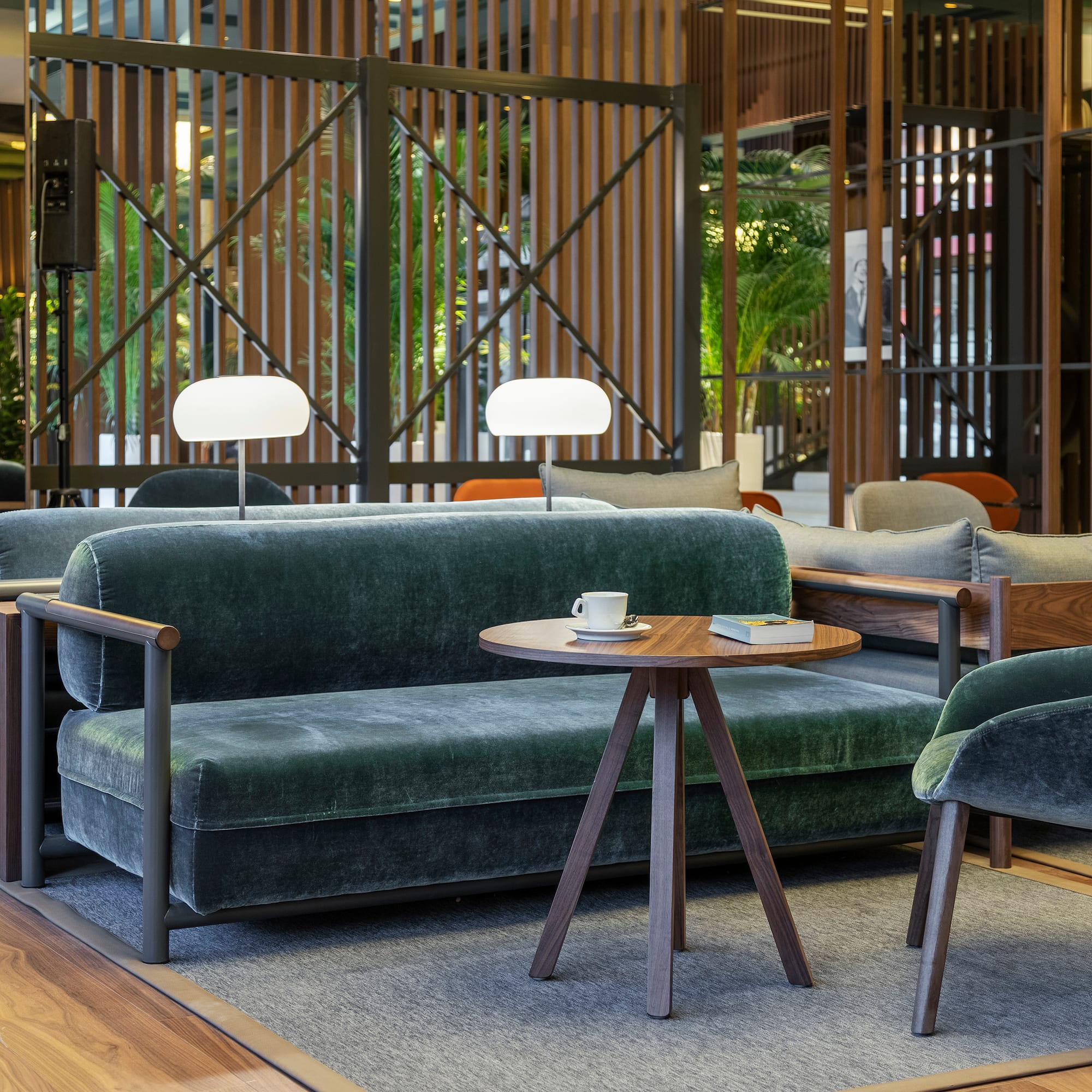 Green velvet lounge seating in a modern hotel lobby with wooden screens.
