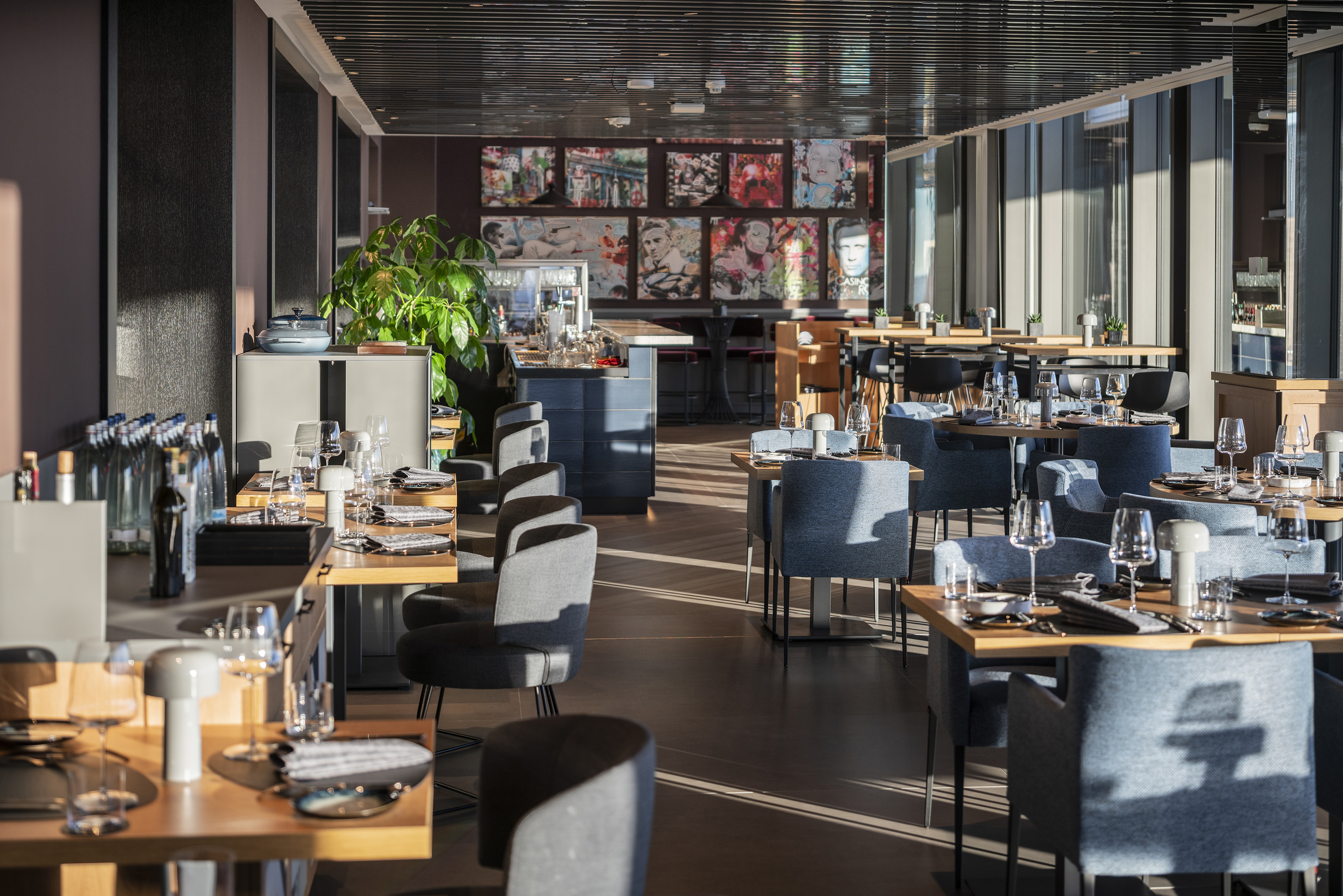 Contemporary restaurant dining area with set tables, blue chairs, and pop art.