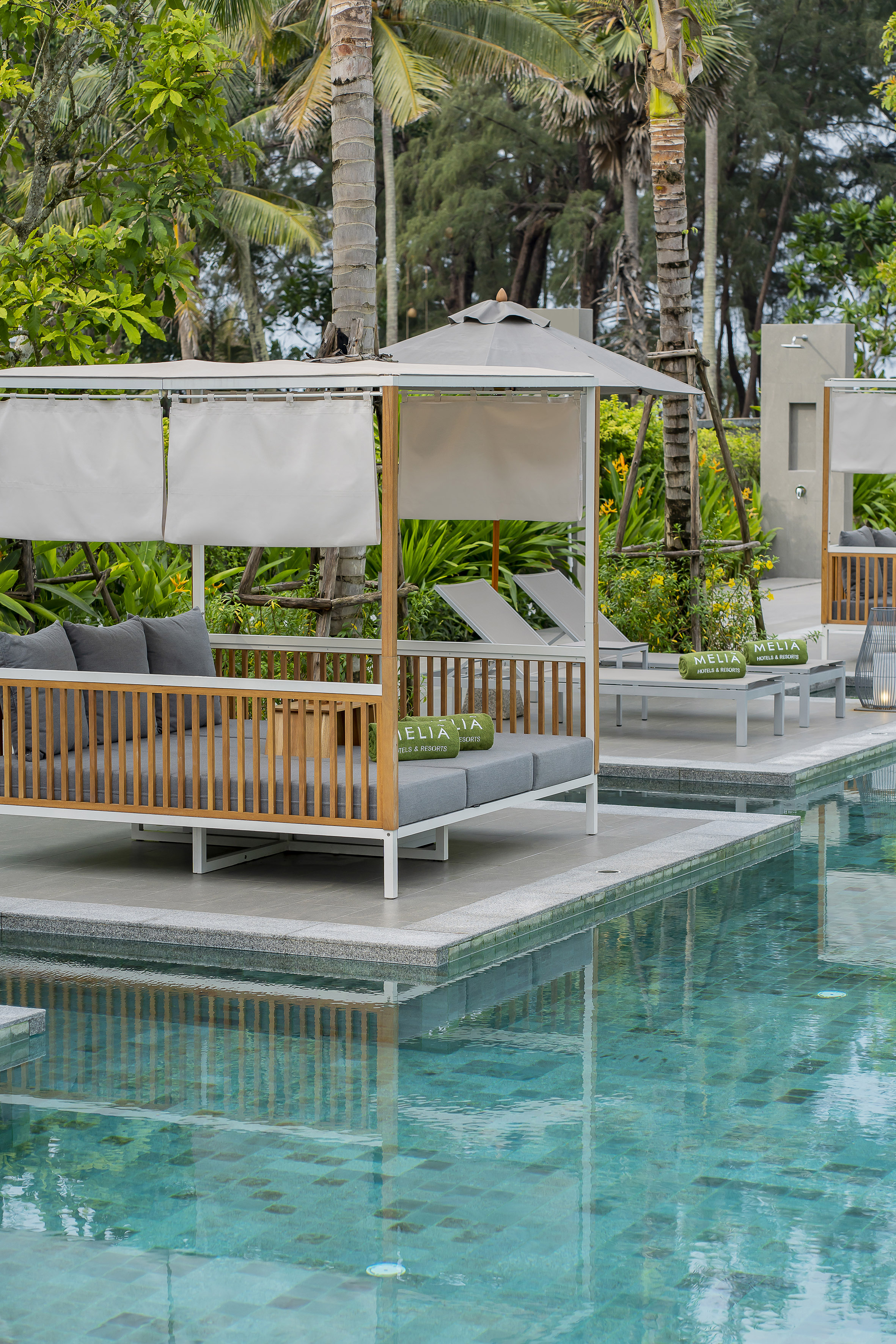 Meliá resort pool with modern cabanas, sun loungers, and lush palm trees.