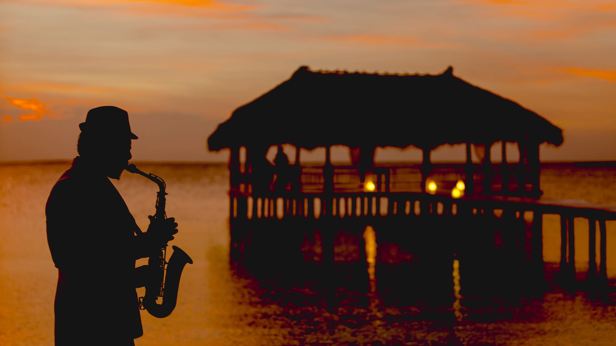 a man playing a saxophone in front of a pier