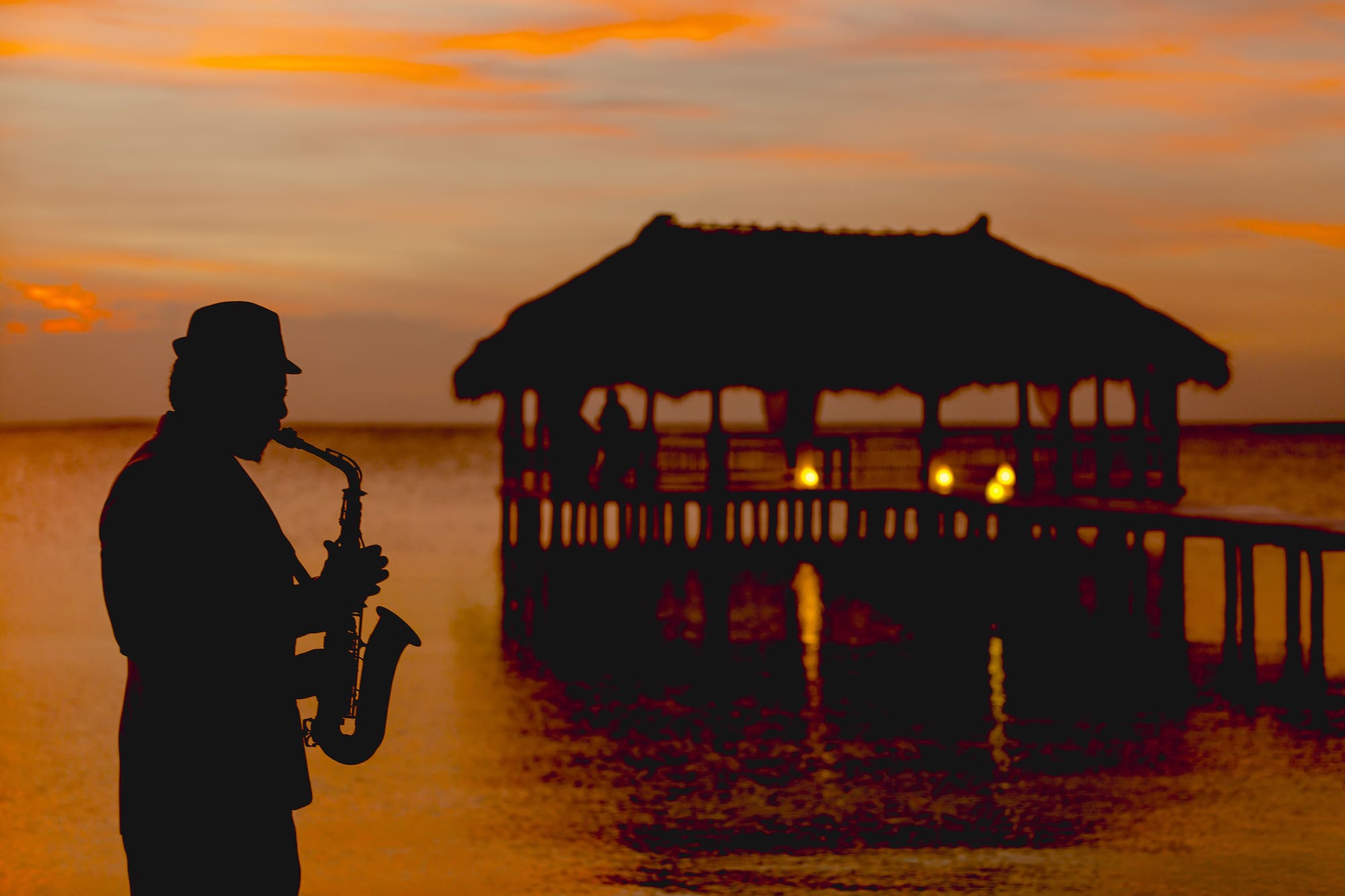 a man playing a saxophone in front of a pier