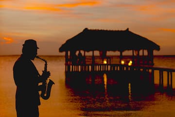 a man playing a saxophone in front of a pier