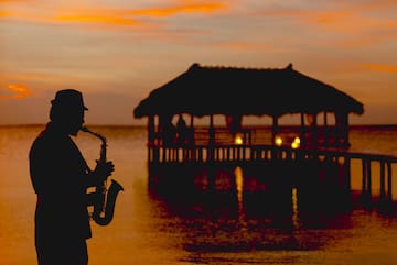 a man playing a saxophone in front of a pier