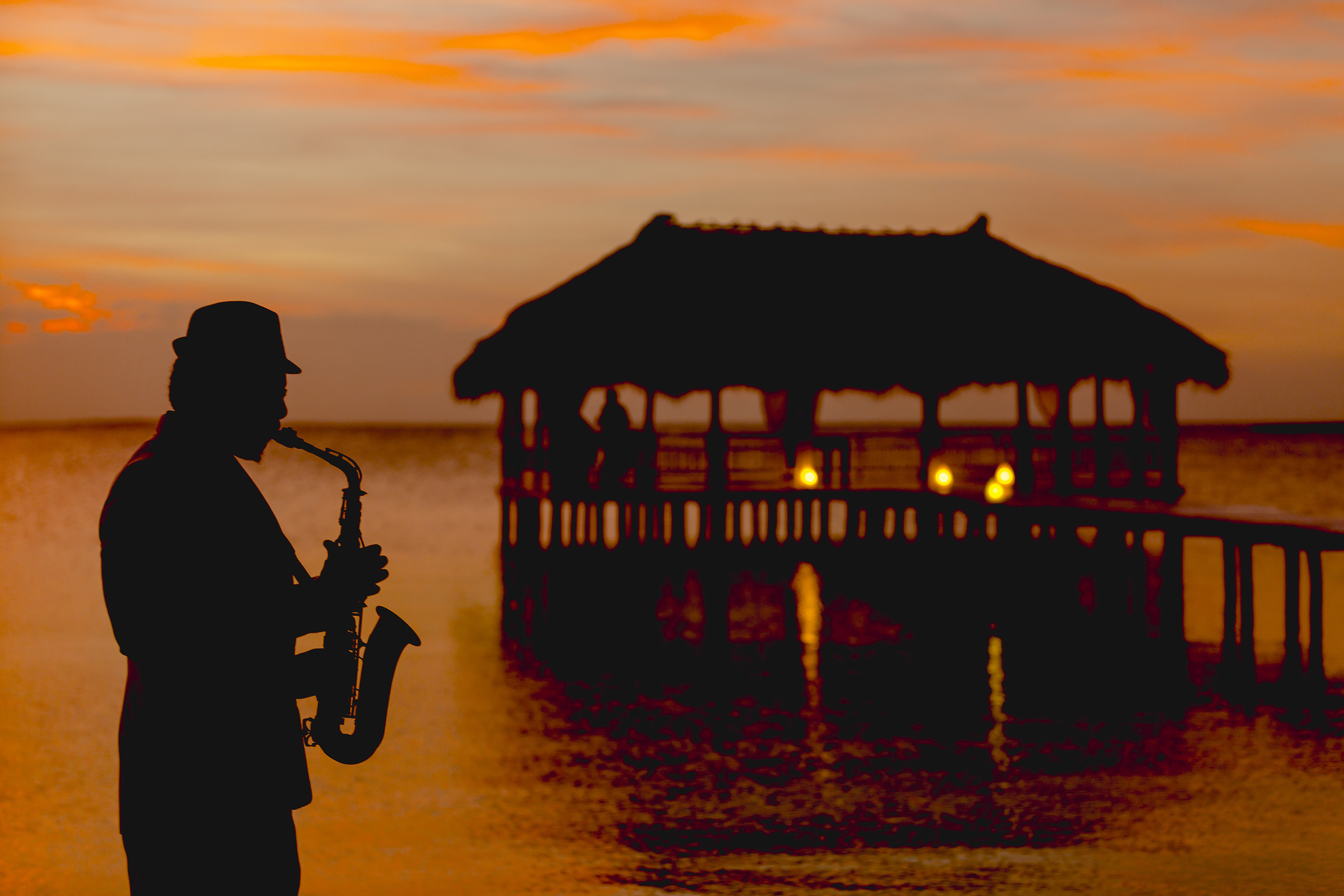 a man playing a saxophone in front of a pier