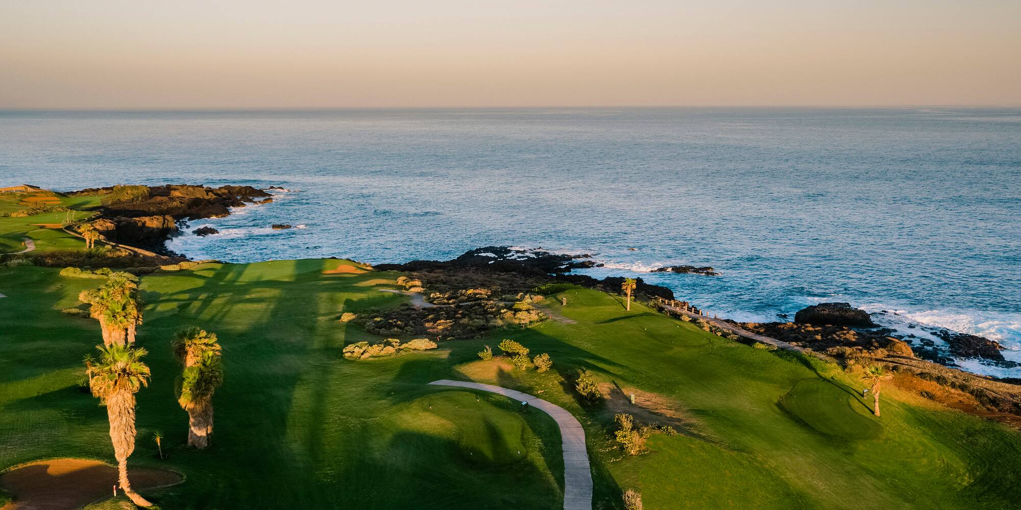 a golf course with a path and a body of water