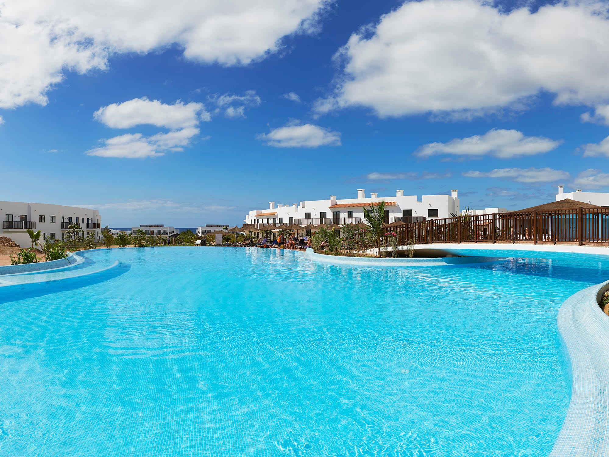 a pool with a bridge and buildings in the background