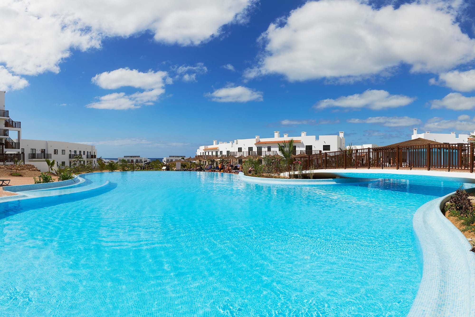 a pool with a bridge and buildings in the background
