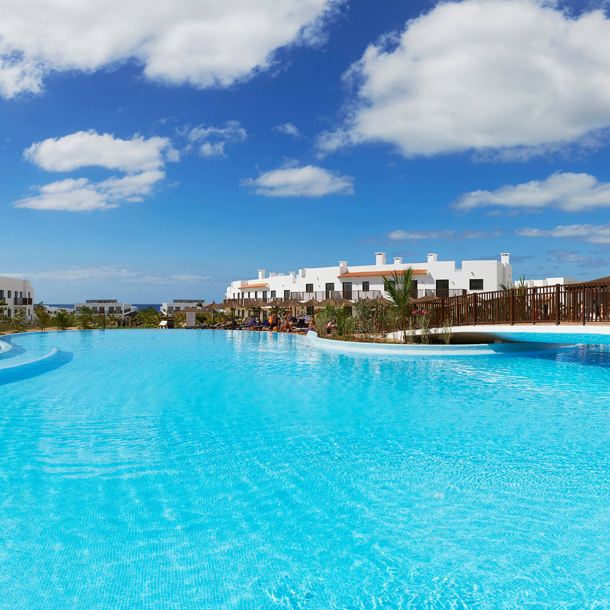 a pool with a bridge and buildings in the background