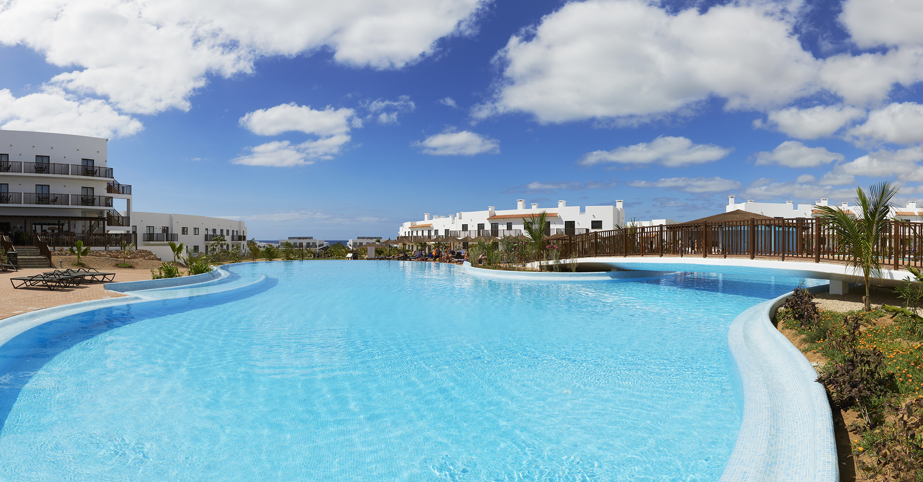 a pool with a bridge and buildings in the background