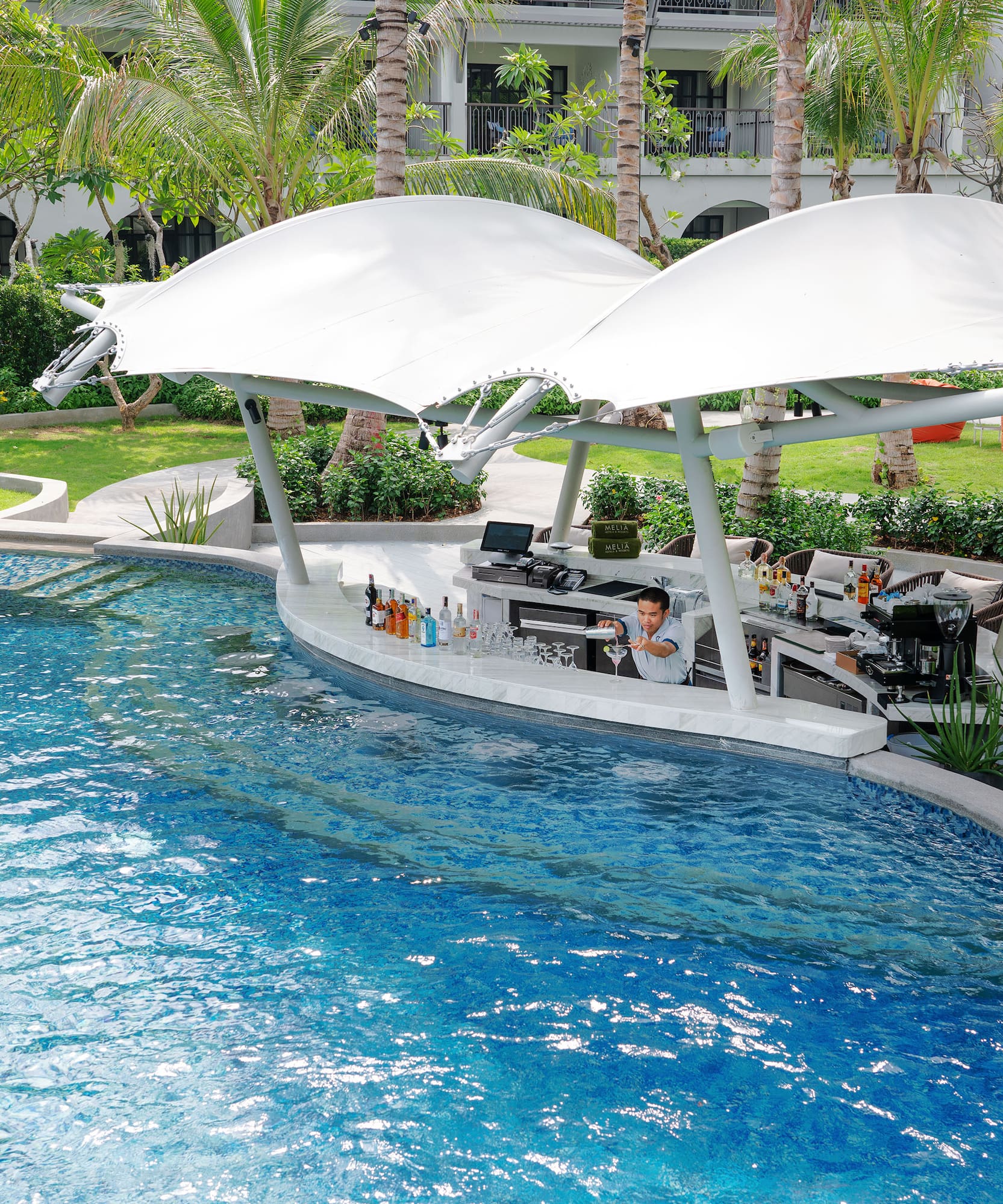 a pool with a bar and a man sitting at it