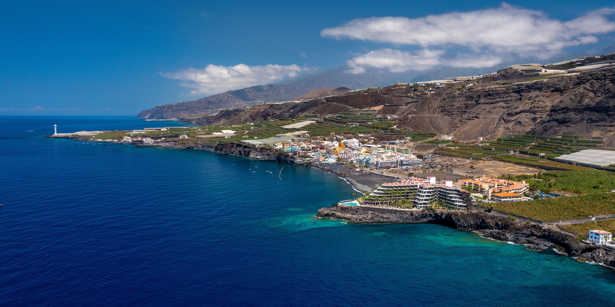 a body of water with buildings and mountains in the background