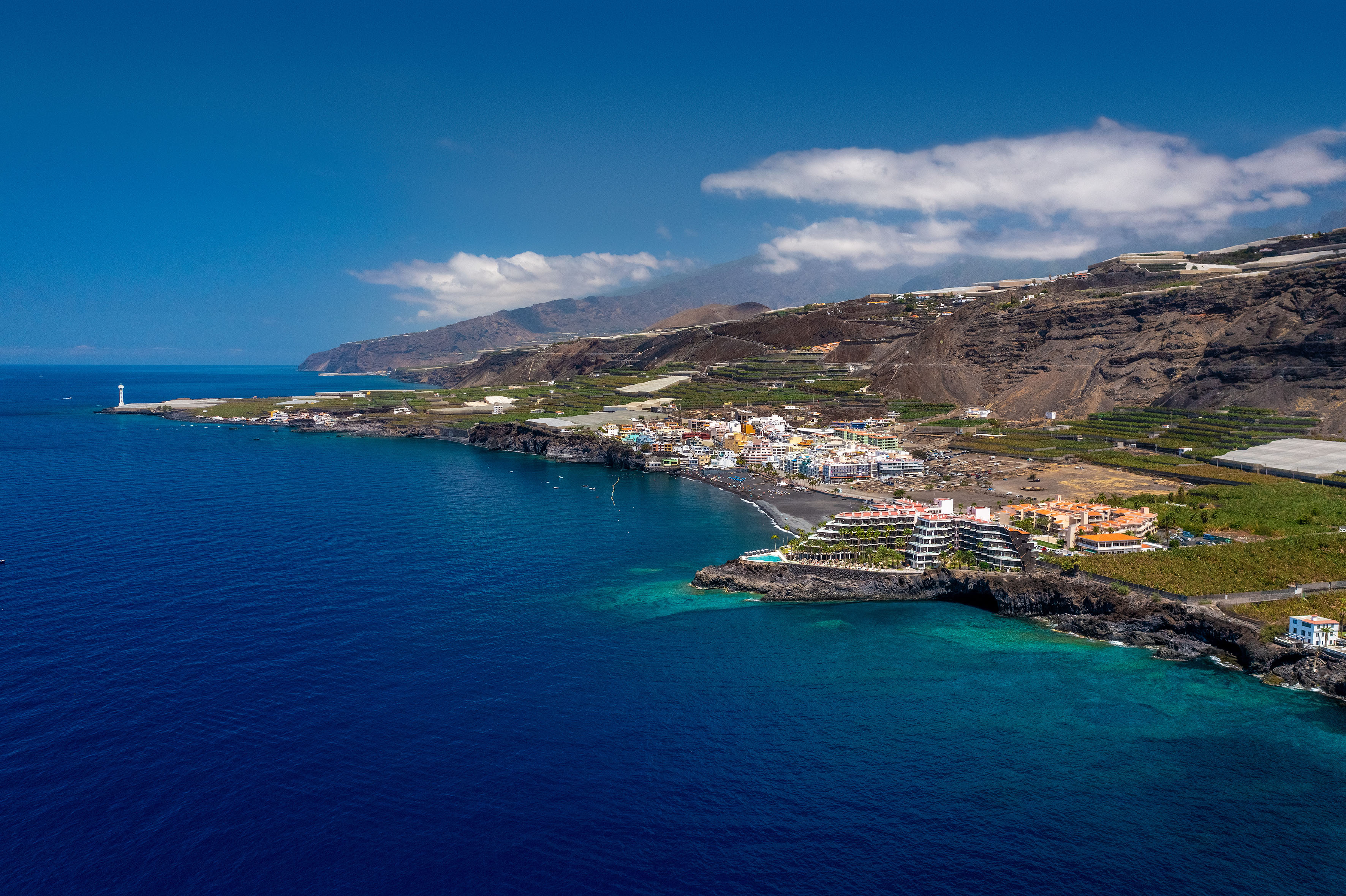La Palma coastal town, black sand beach, ocean, lighthouse, and mountains.