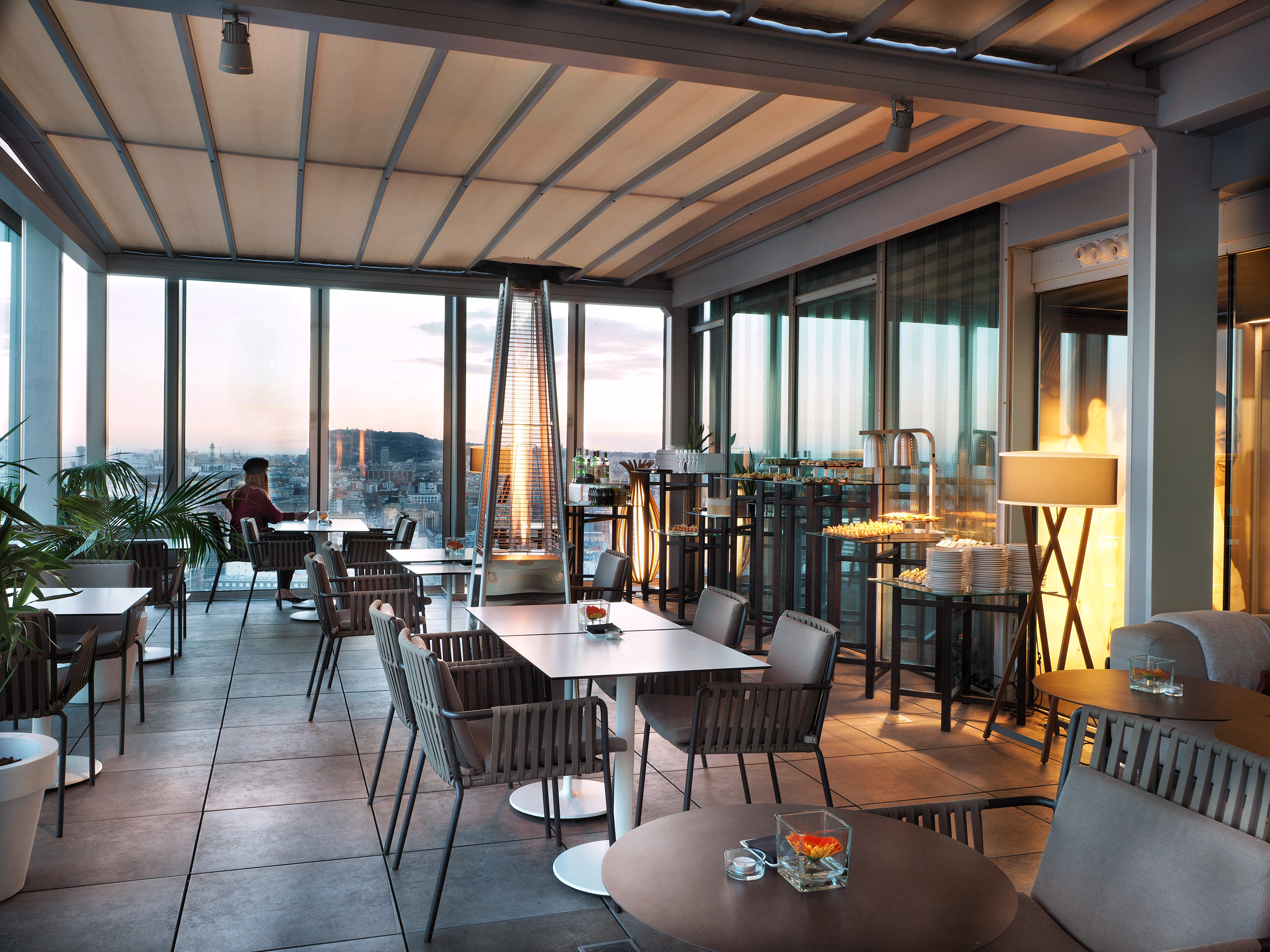 Stylish rooftop lounge with city skyline view and patio heater.