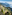 Terraced Mediterranean coast with a winding road, green hills, and blue sea.