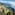 Terraced Mediterranean coast with a winding road, green hills, and blue sea.