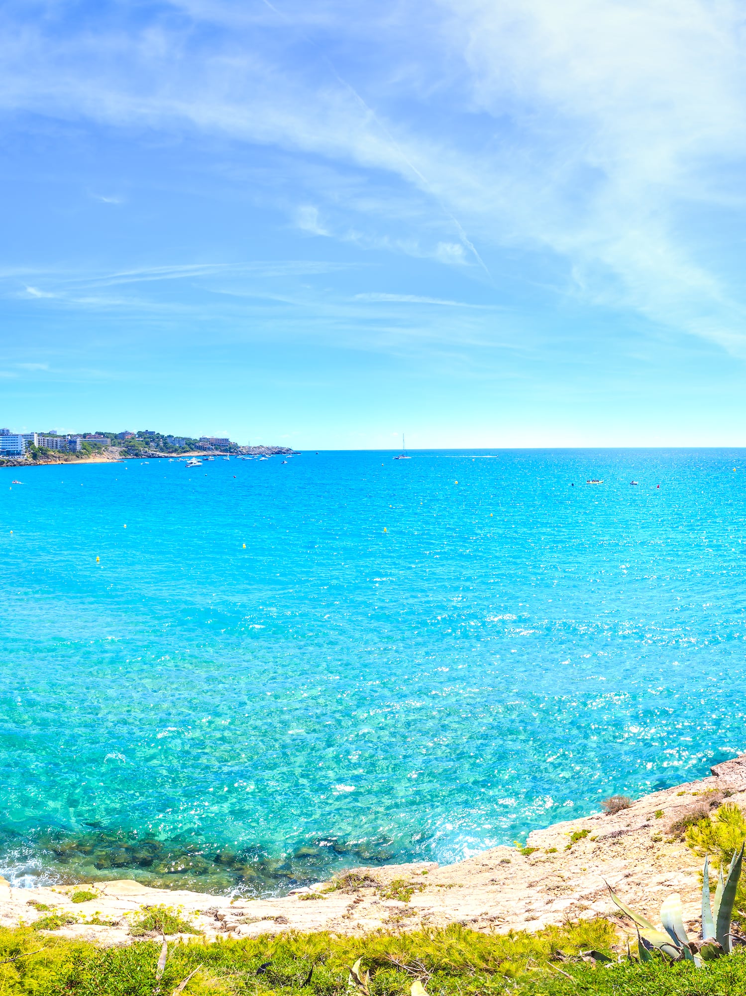 a blue water with a beach and buildings in the background