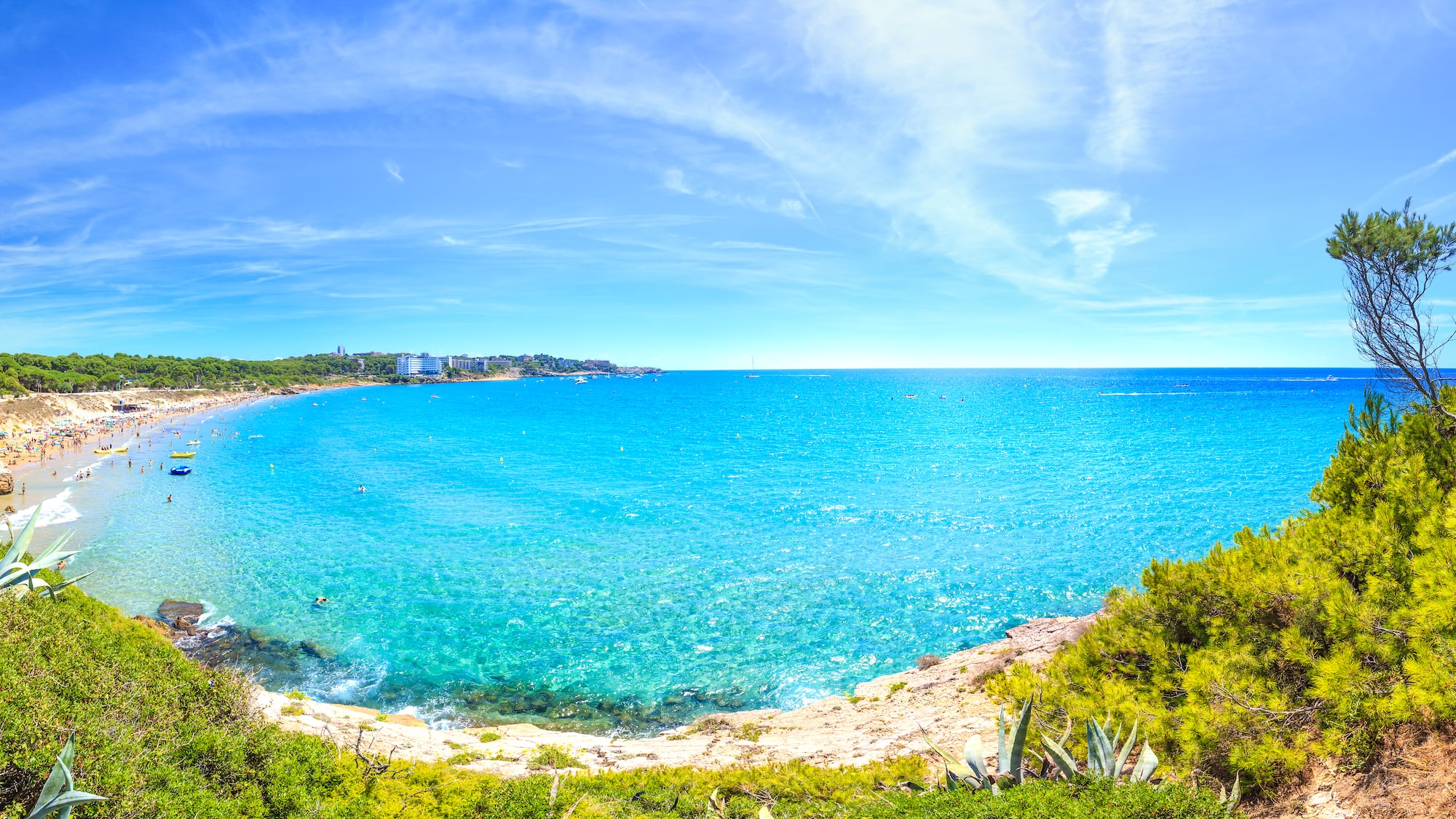 a blue water with a beach and buildings in the background