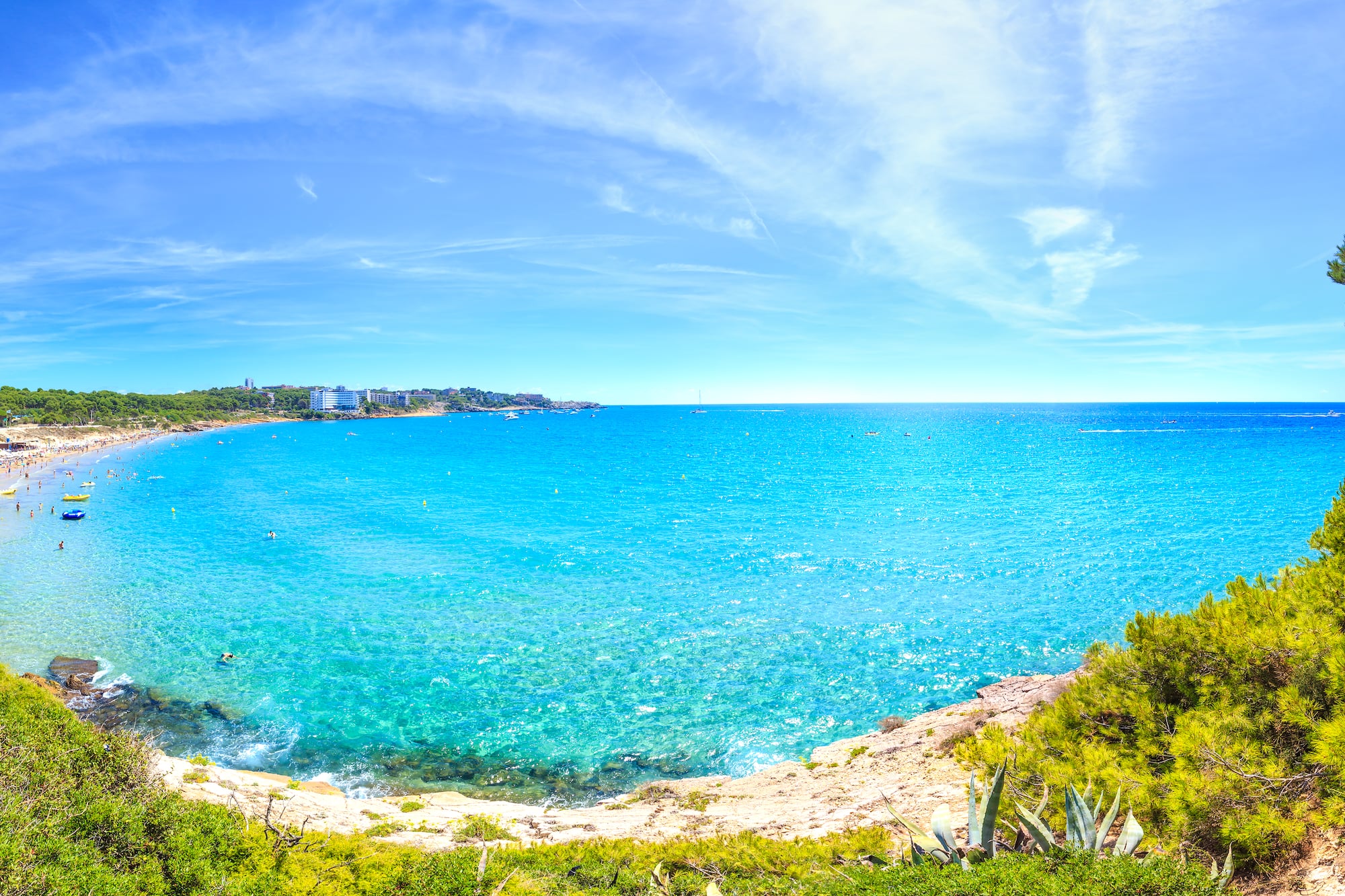 a blue water with a beach and buildings in the background