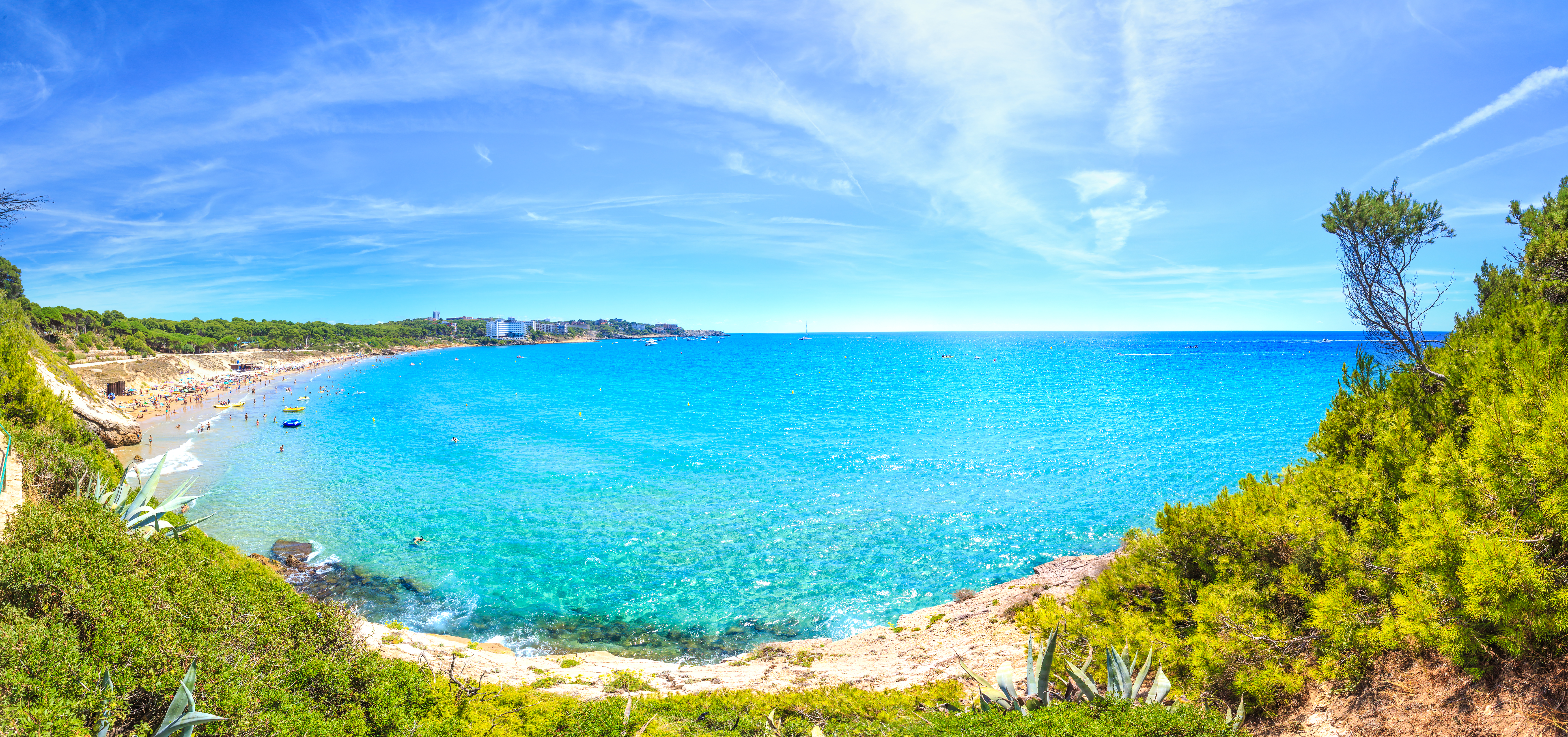a blue water with a beach and buildings in the background