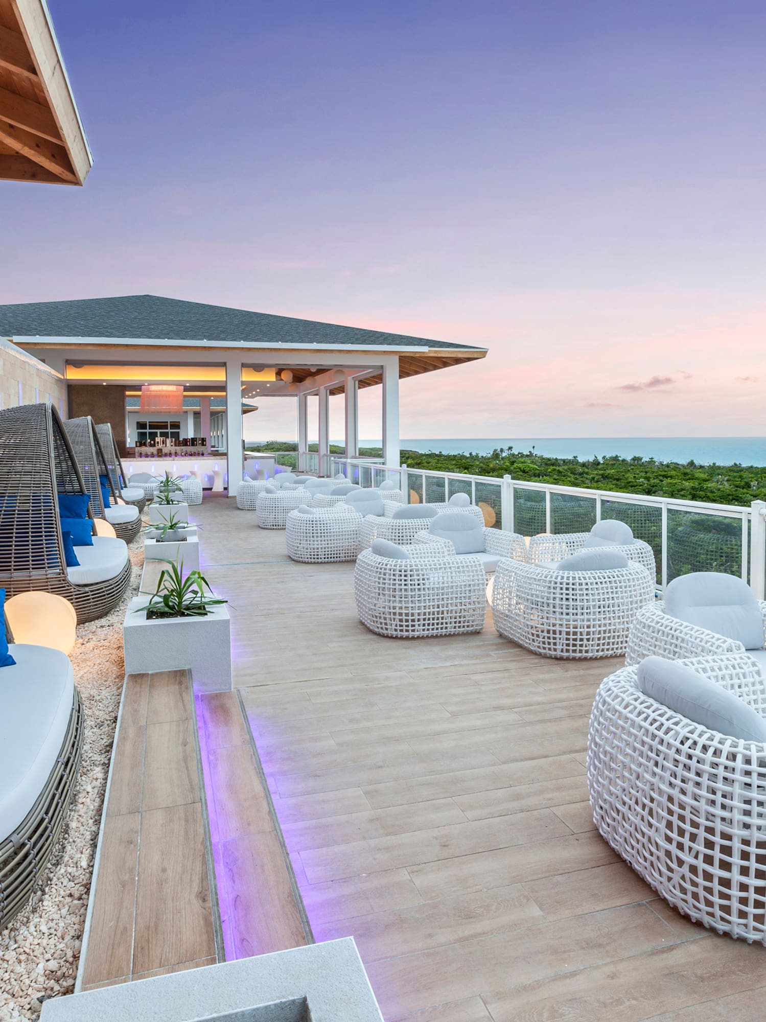 a patio with white wicker furniture and a fence