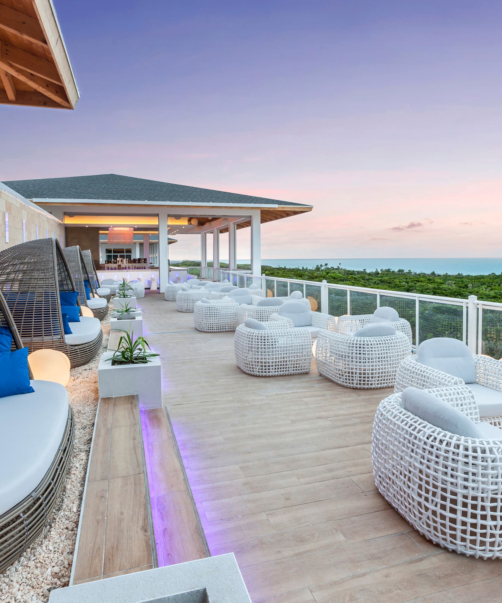 a patio with white wicker furniture and a fence
