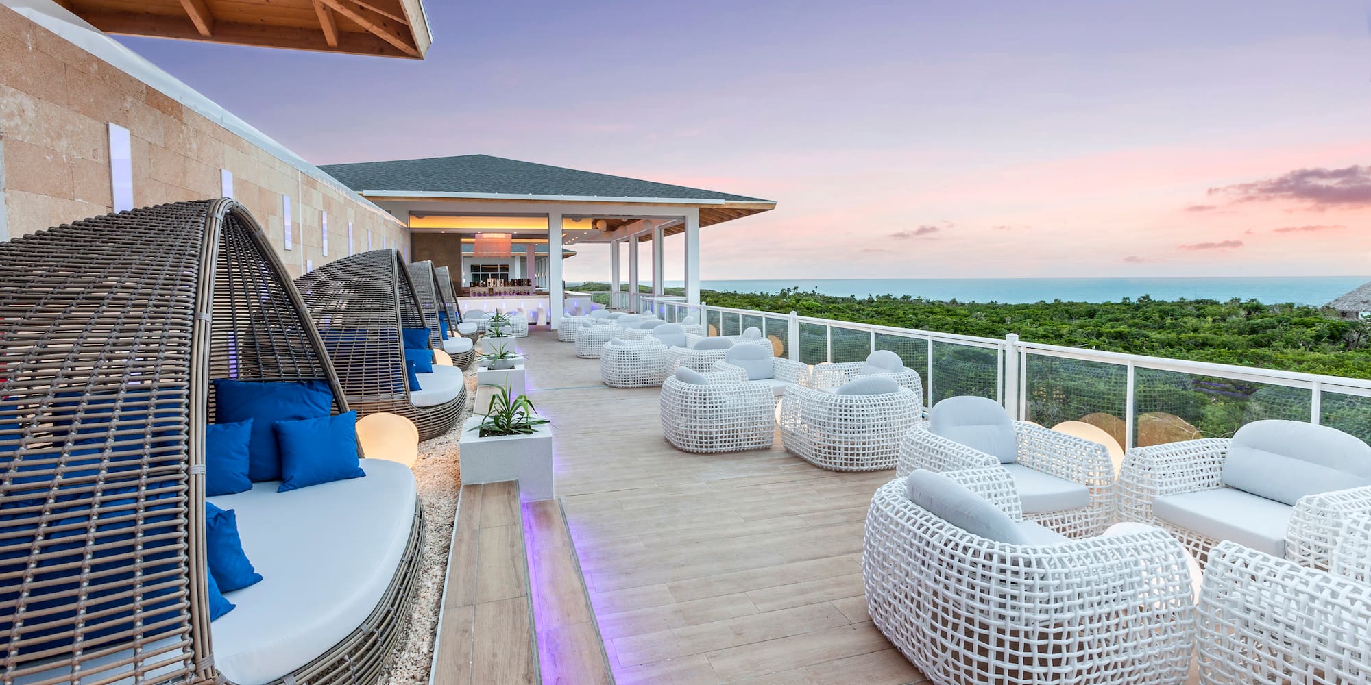 a patio with white wicker furniture and a fence