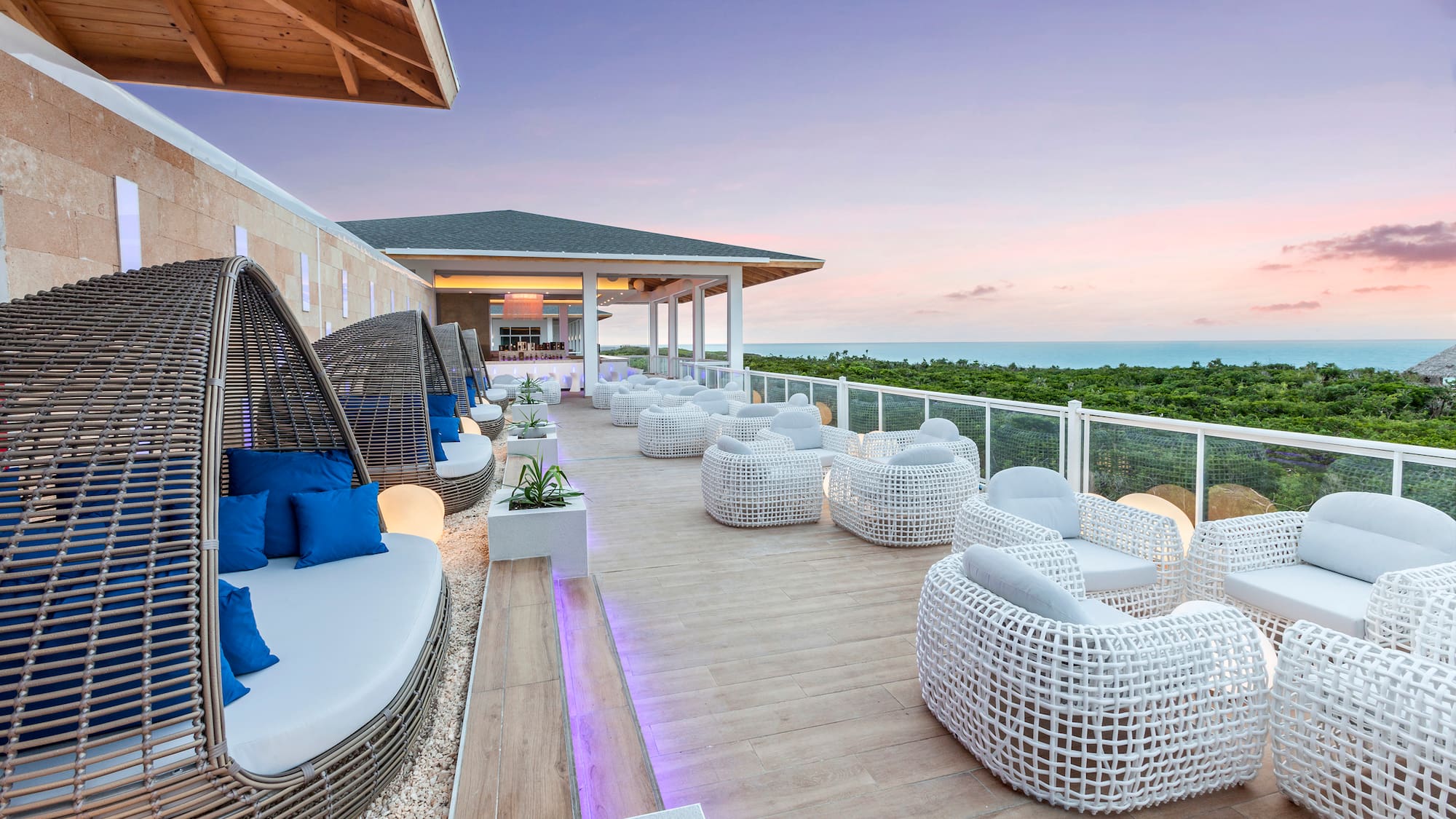a patio with white wicker furniture and a fence