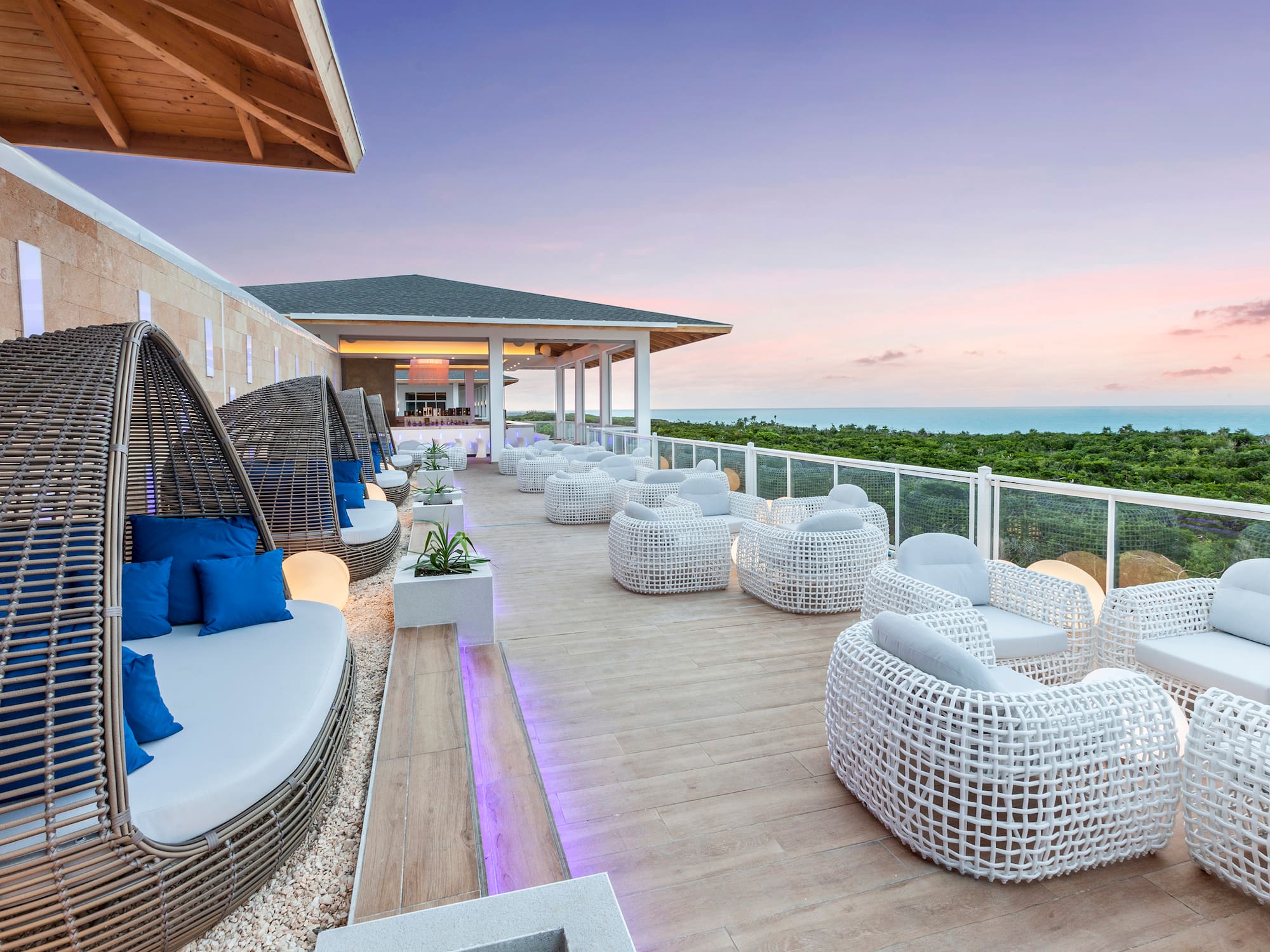 a patio with white wicker furniture and a fence