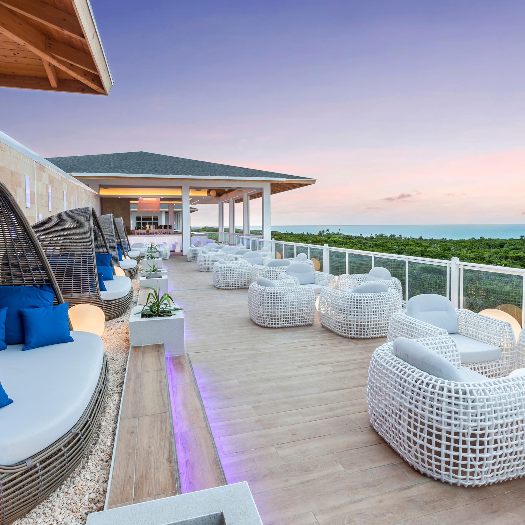 a patio with white wicker furniture and a fence