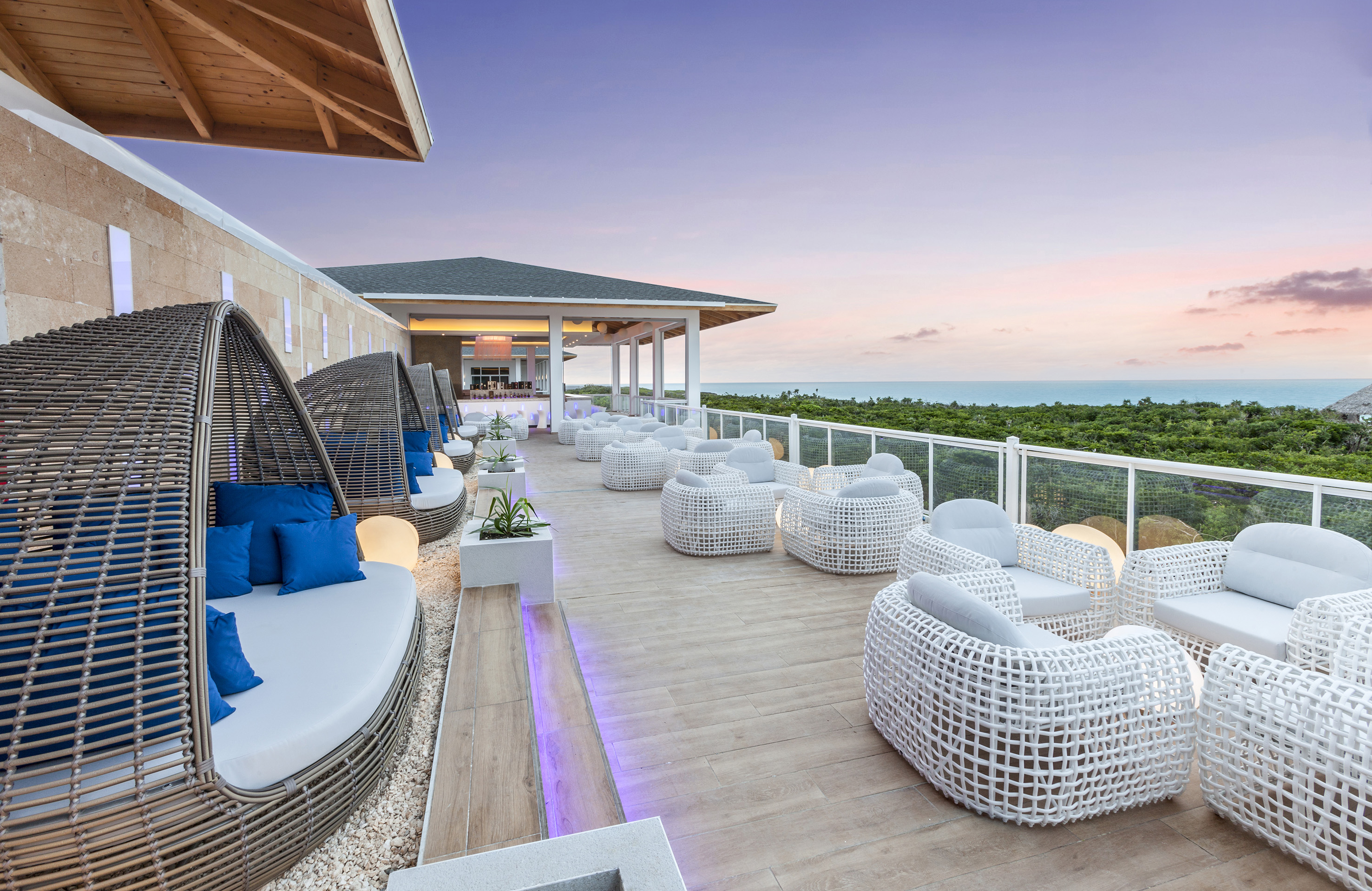 a patio with white wicker furniture and a fence