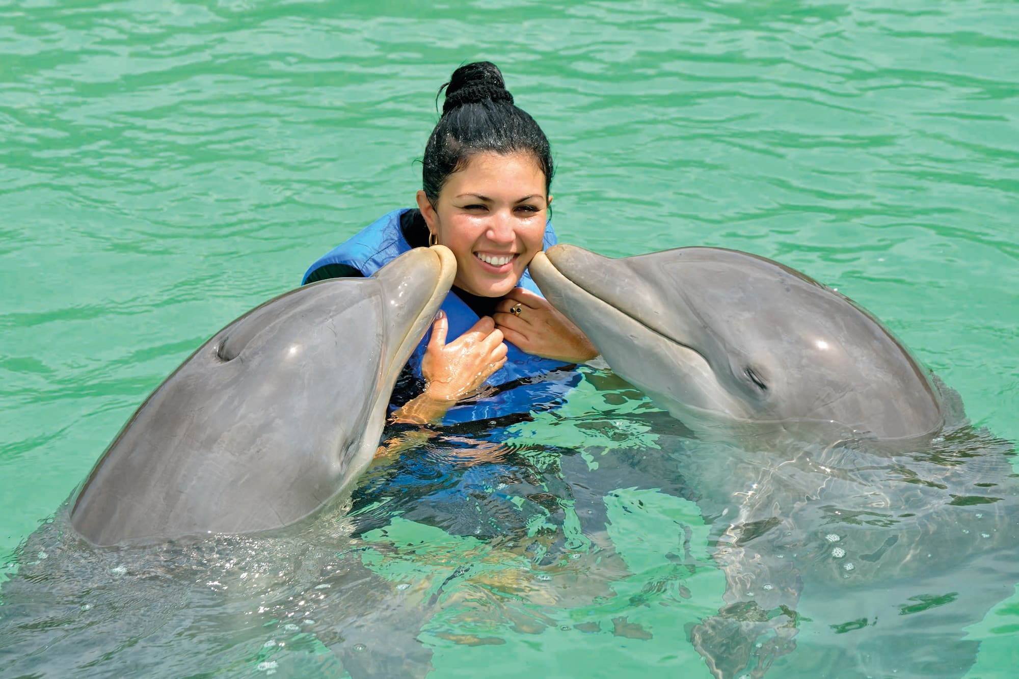 a woman with two dolphins in water