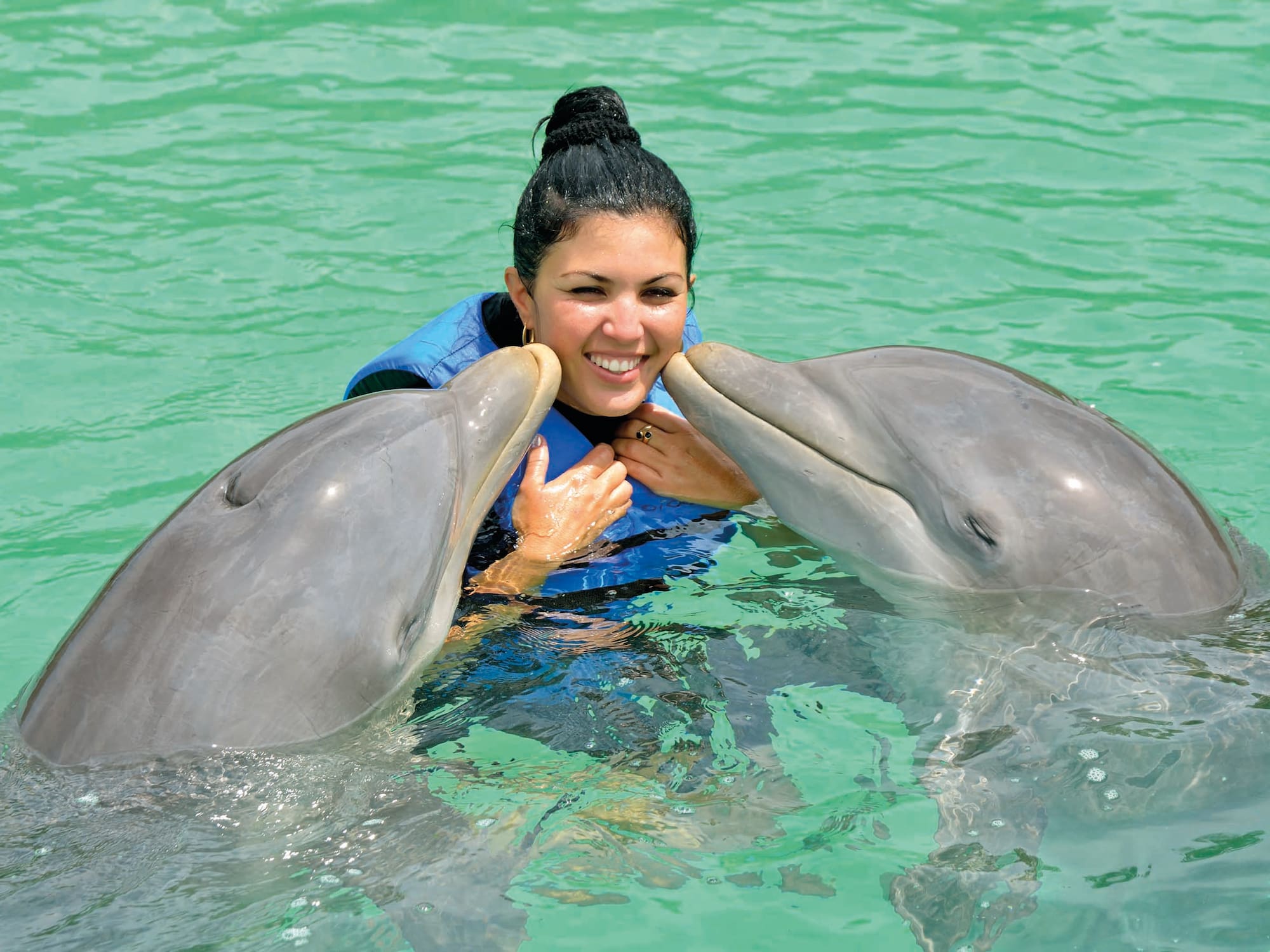 a woman with two dolphins in water
