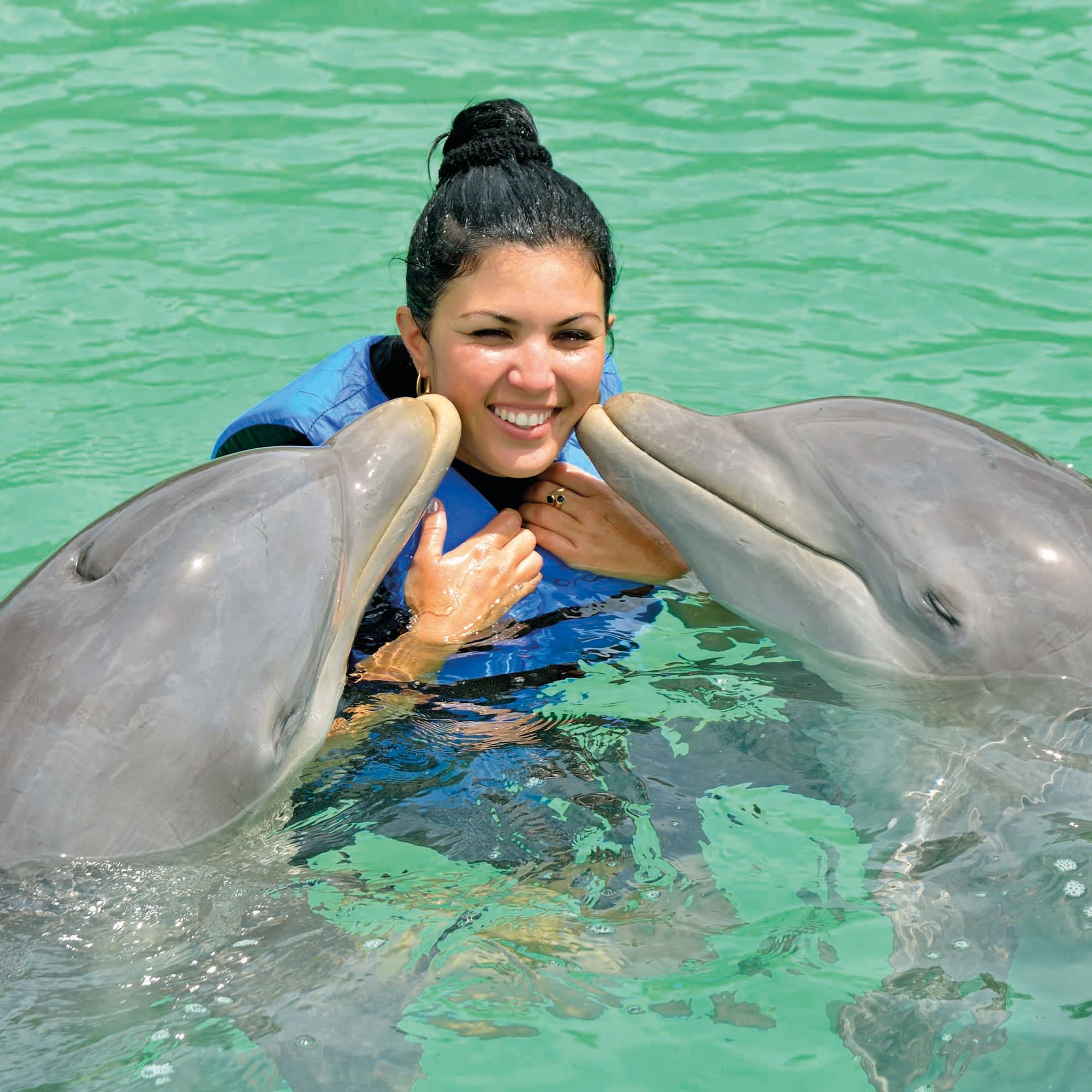 a woman with two dolphins in water