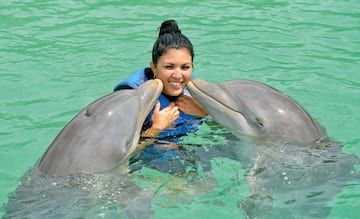 a woman with two dolphins in water