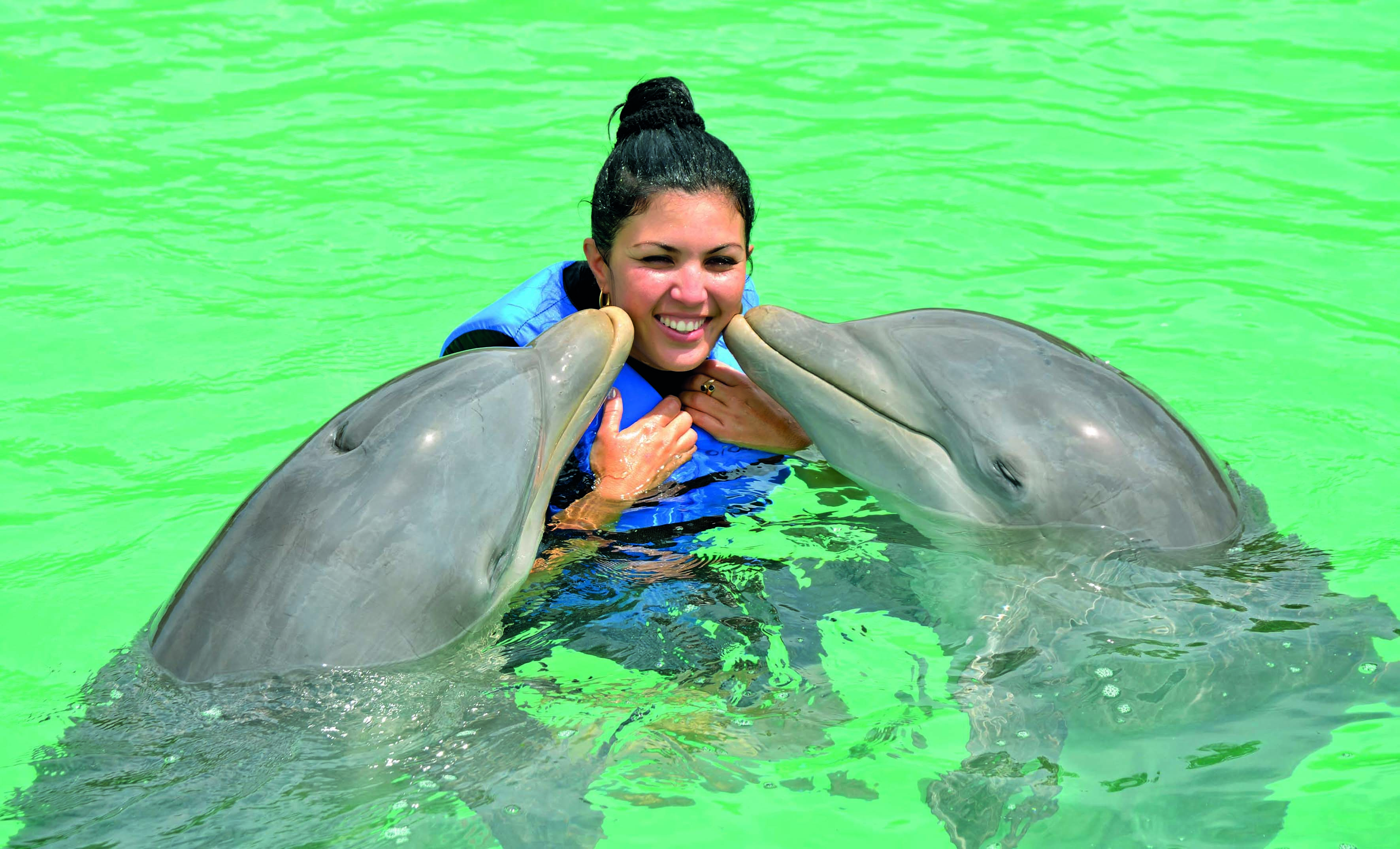 a woman with two dolphins in water