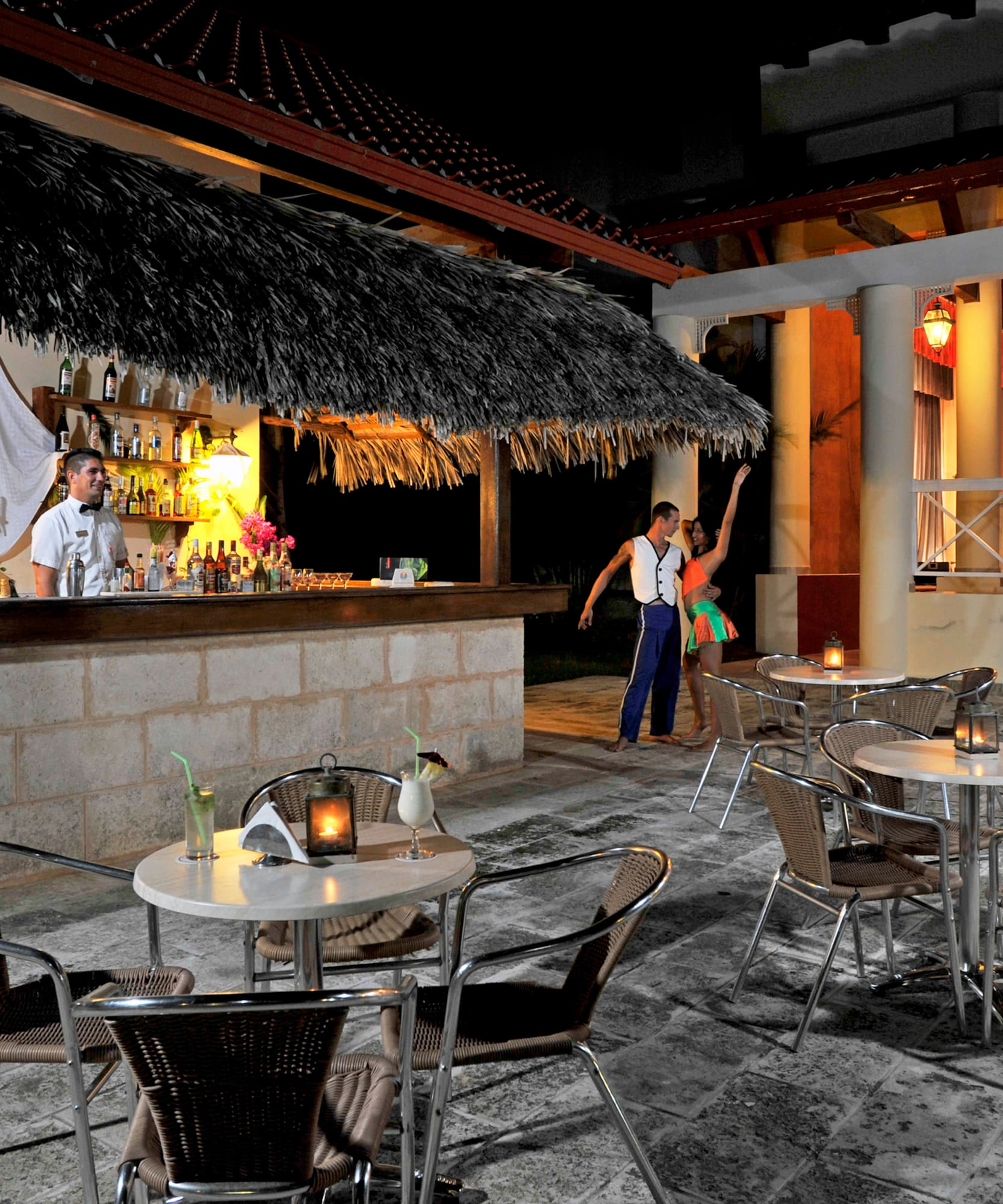 a group of people standing around tables and chairs outside a bar