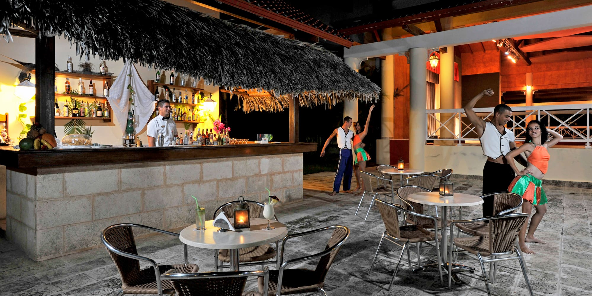 a group of people standing around tables and chairs outside a bar