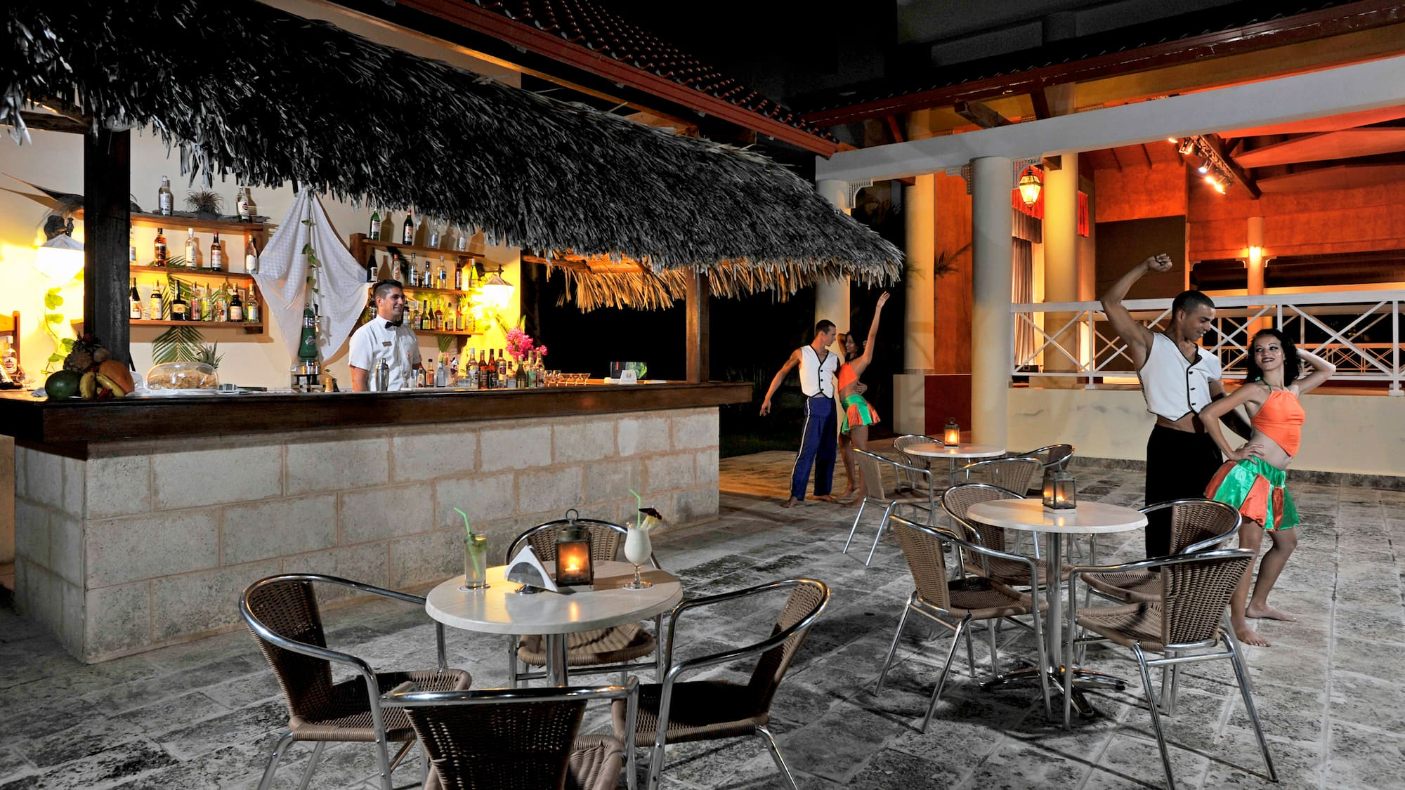 a group of people standing around tables and chairs outside a bar