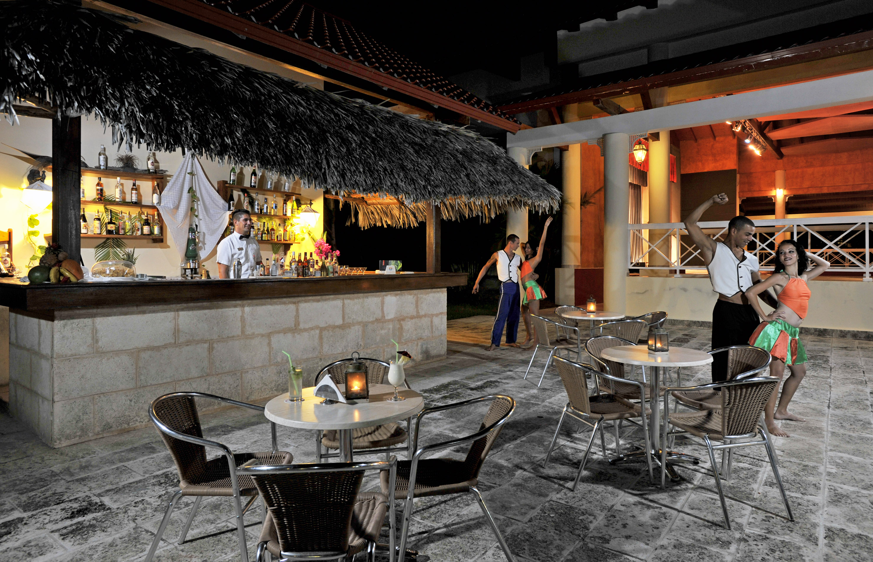 a group of people standing around tables and chairs outside a bar