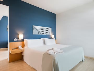 a bed with white sheets and a blue wall