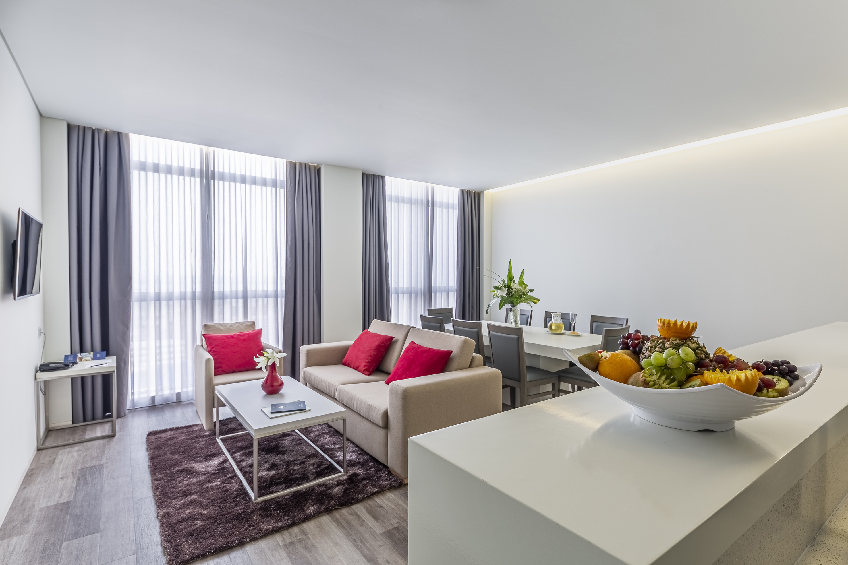 Contemporary living room suite with sofa, dining area, and fresh fruit bowl.