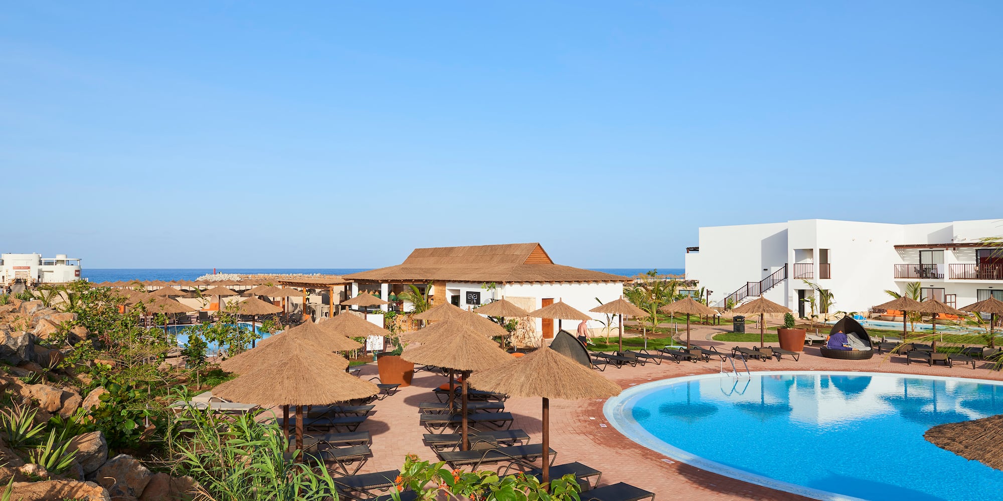 a pool with umbrellas and chairs and a building with a body of water